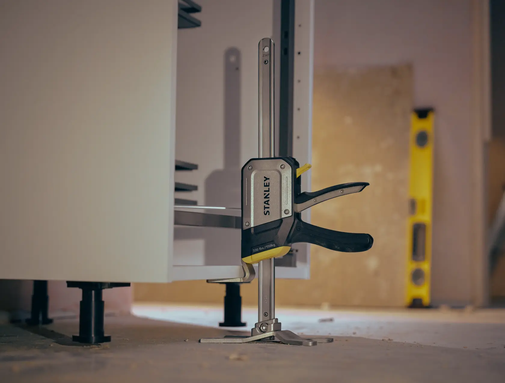 STANLEY FMHT83550-1 clamp securing cabinet, photography from side angle on workshop floor.