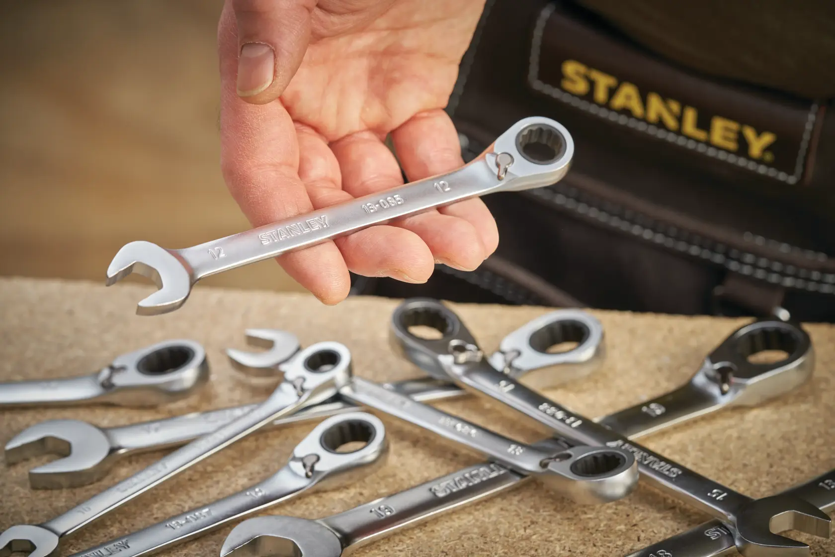 Photo of STANLEY FMMT13083-0 ratcheting combination wrenches on a workbench, one held in hand, brand name visible.