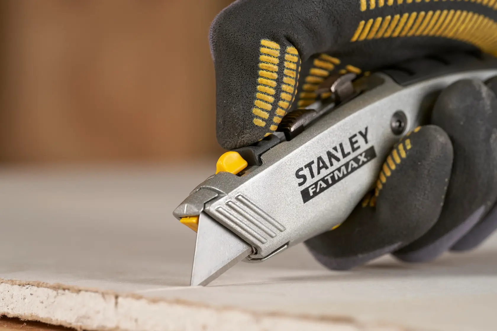 Stanley 0-10-789 utility knife in use, cutting drywall, close-up photo with gloved hand.