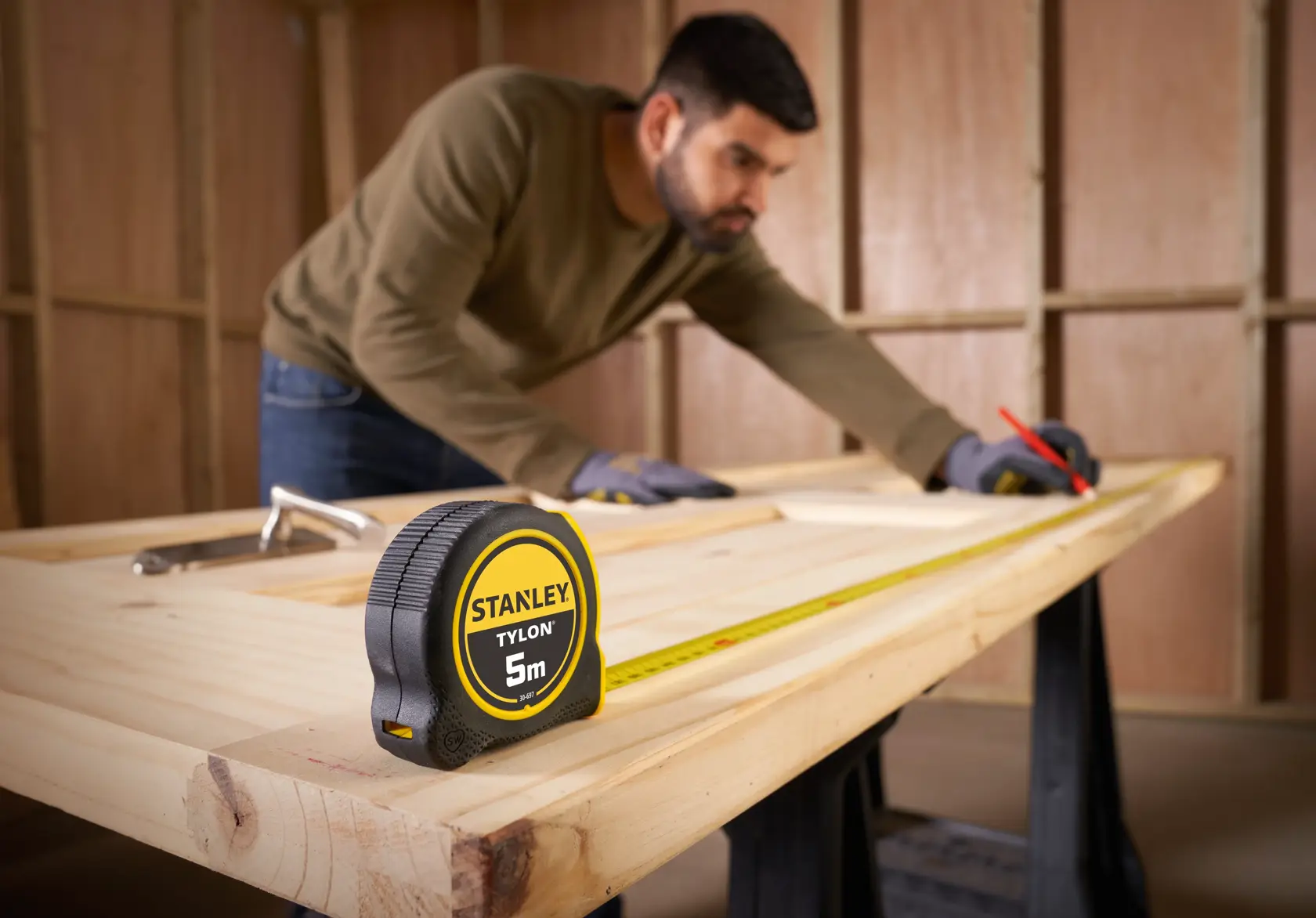 STANLEY 0-30-697 Maßband auf Holzbock mit Person, die Holz markiert, Werkstattszene.