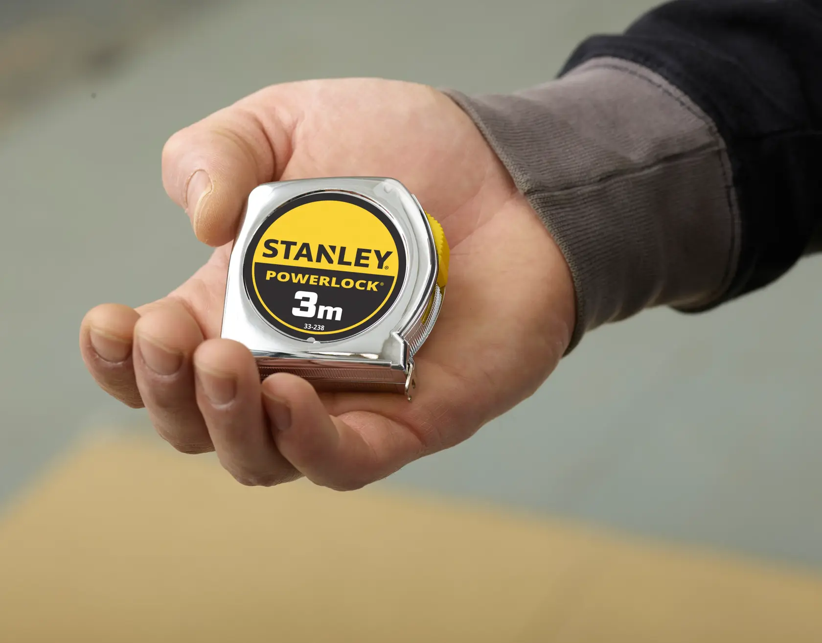 Photo of STANLEY 0-33-238 PowerLock tape measure in a hand, yellow and black, 3m length, photography category.