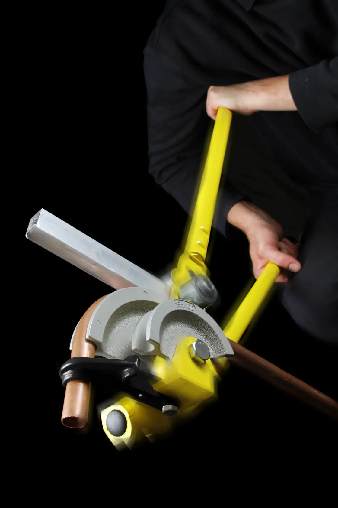 STANLEY 0-70-452 pipe bender being used to bend copper pipe with yellow handles, close-up photography.