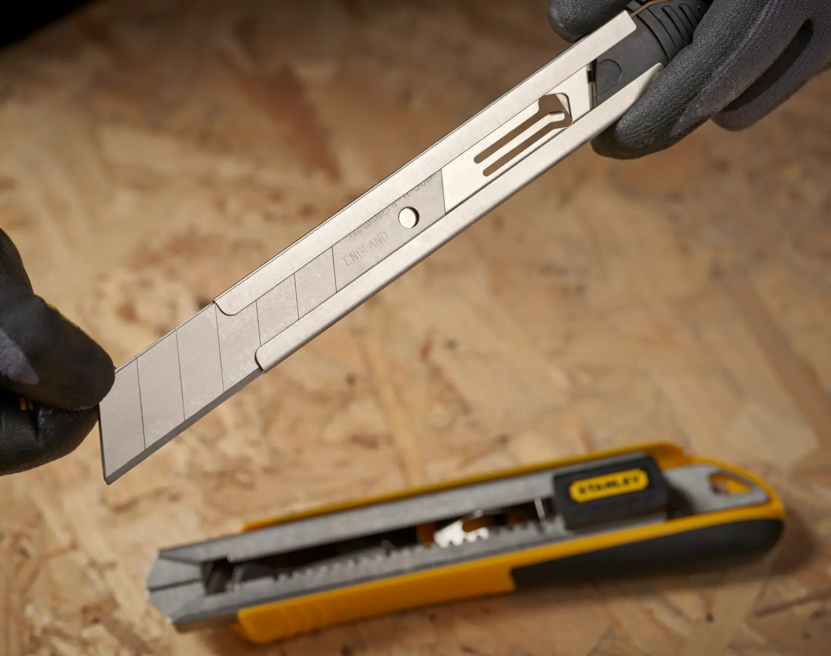 Stanley 1-11-325 utility knife blade with segments, shown in close-up during replacement, utility knife below.