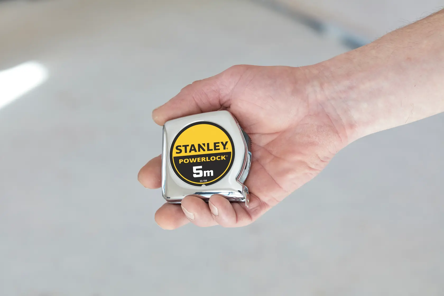 STANLEY 1-33-194 Maßband PowerLock 5m in einer Hand gehalten, Nahaufnahme.
