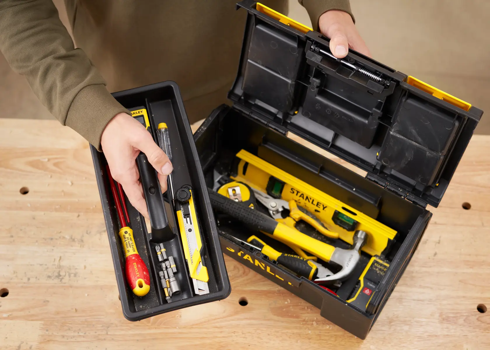STANLEY 1-79-216 plastic toolbox open with tools on wooden table, top view.
