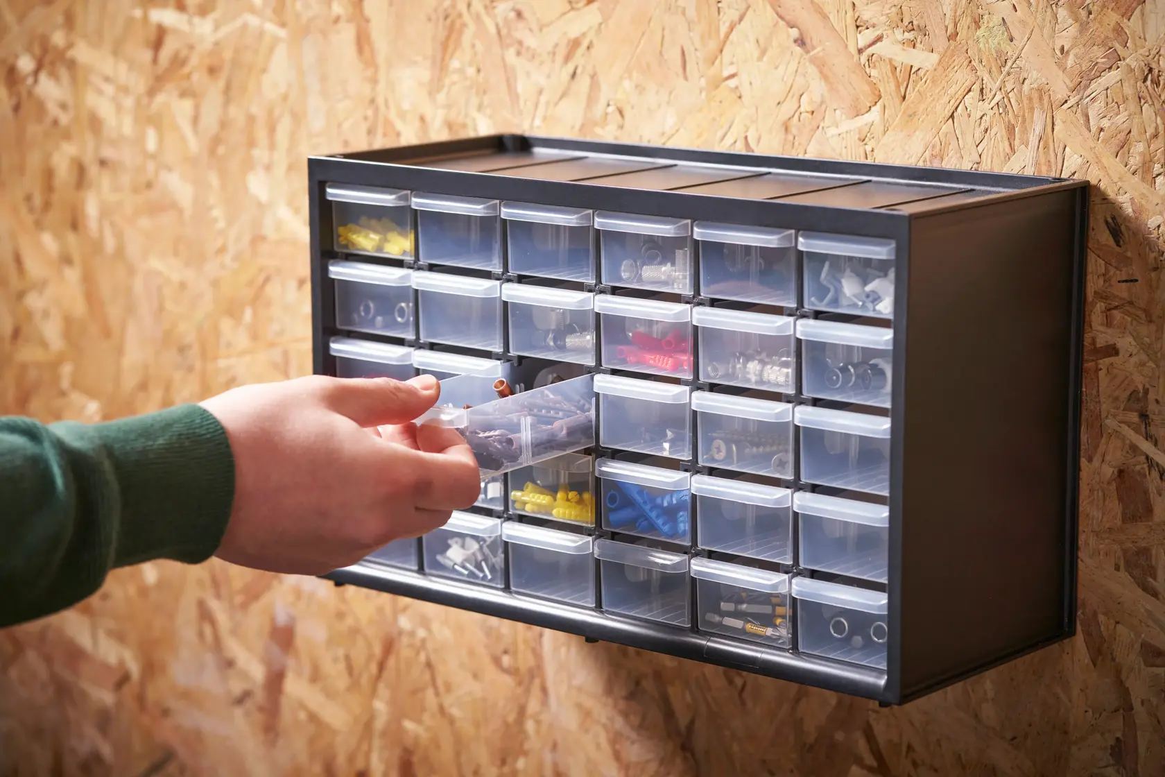 STANLEY 1-93-980 organizer cabinet with clear drawers, wall-mounted, hand pulling out a drawer, photography side angle.