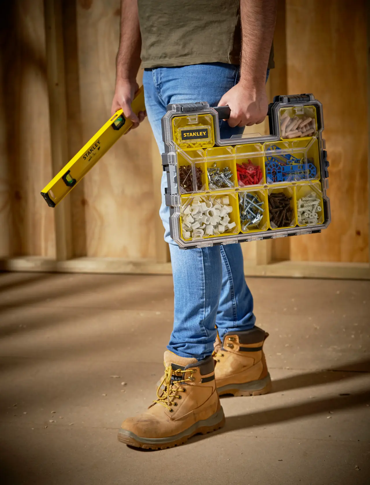 STANLEY 1-97-519 organizer box with yellow compartments, carried by person wearing work boots.