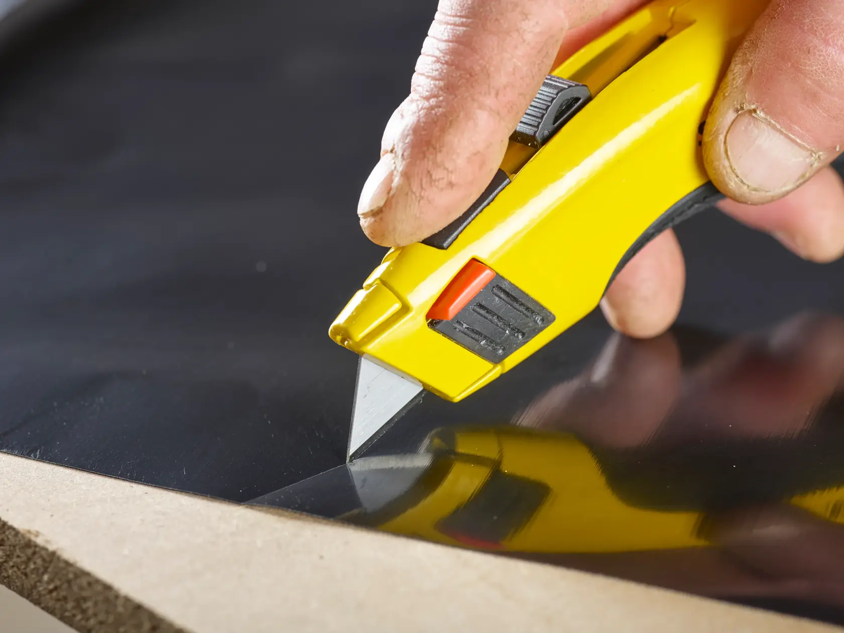 STANLEY 8-11-921 utility knife cutting black material, close-up shot.