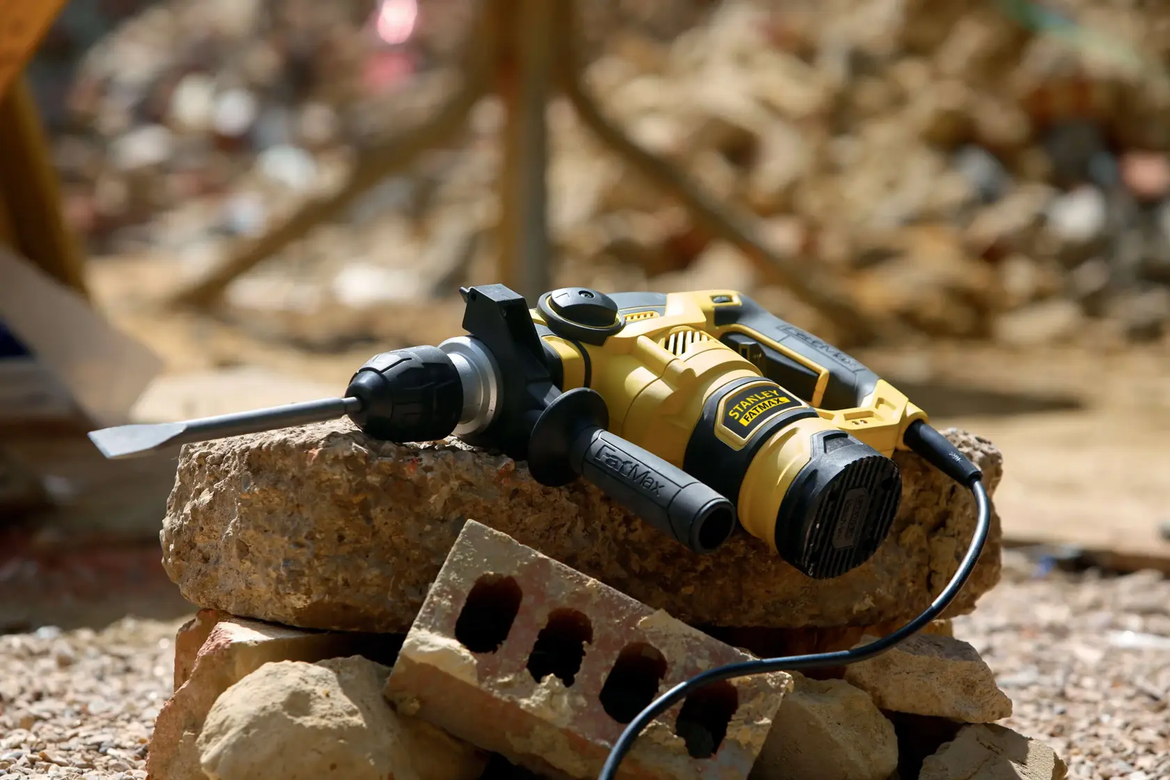 STANLEY FME1250K rotary hammer drill with chisel bit on construction debris, shown in outdoor setting.