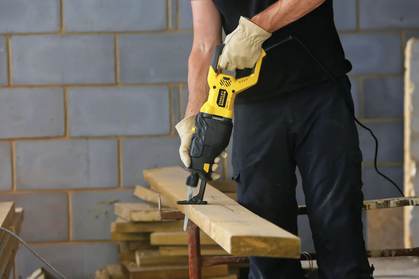 STANLEY FME365K reciprocating saw in use cutting wood plank, construction setting, product demonstration.