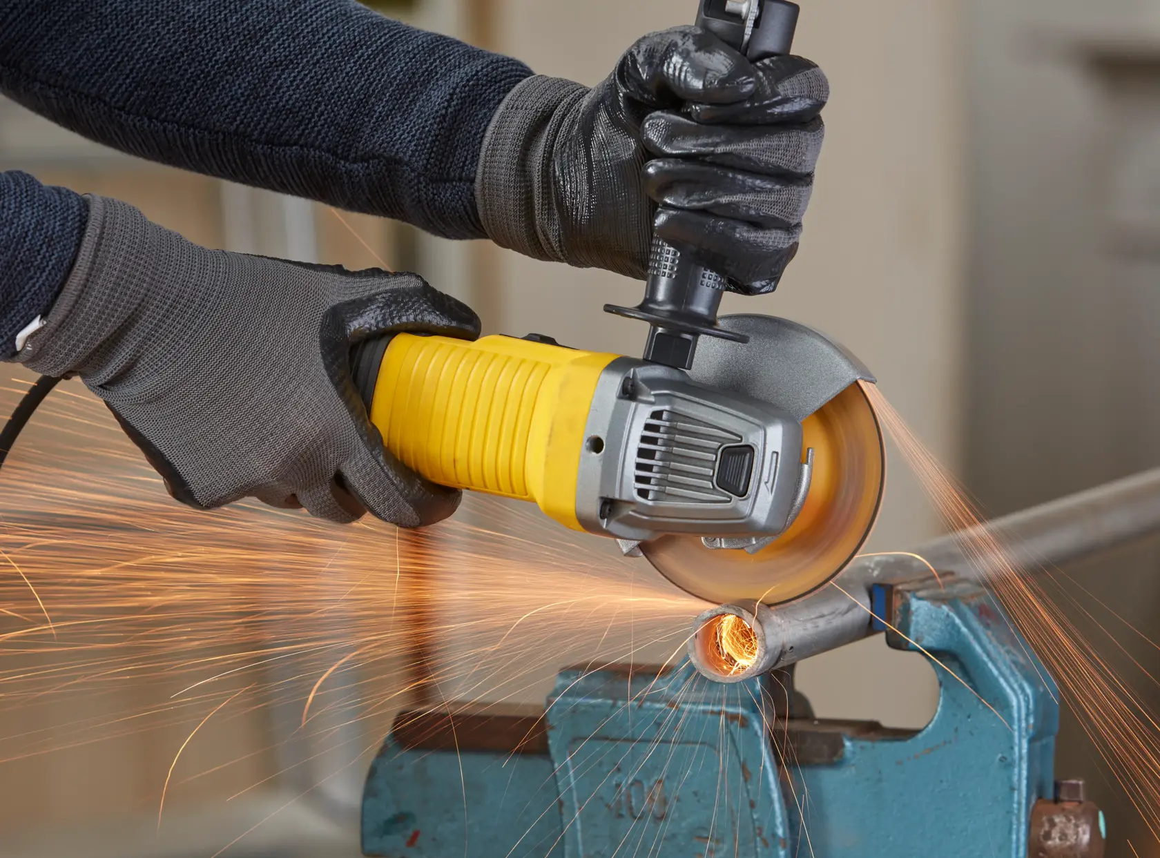 STANLEY FMEG220K angle grinder in use, cutting metal pipe and producing sparks, close-up view.