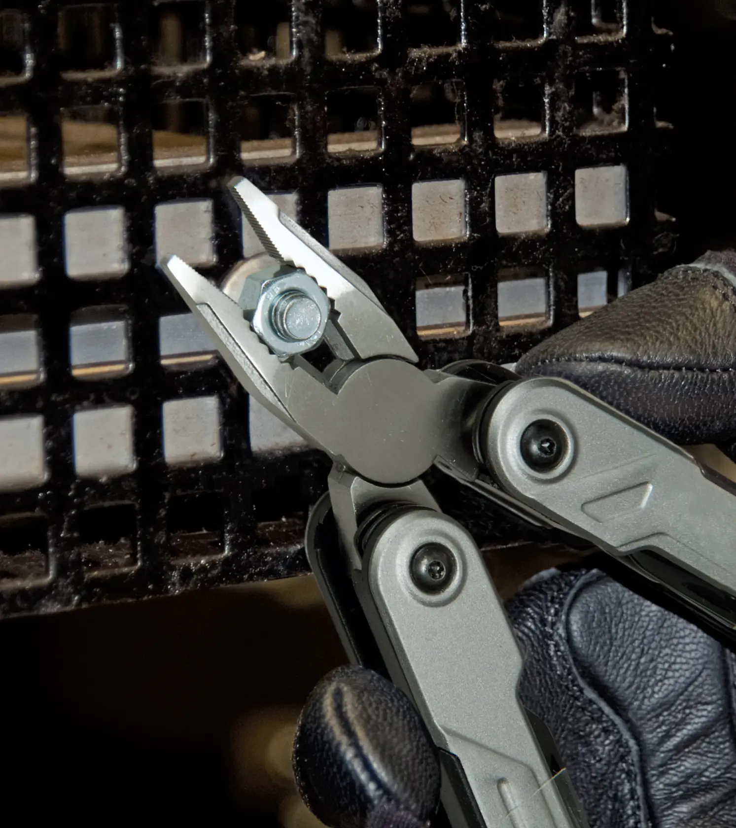 STANLEY FMHT0-72414 multi-tool pliers gripping a bolt, close-up view with gloved hand.