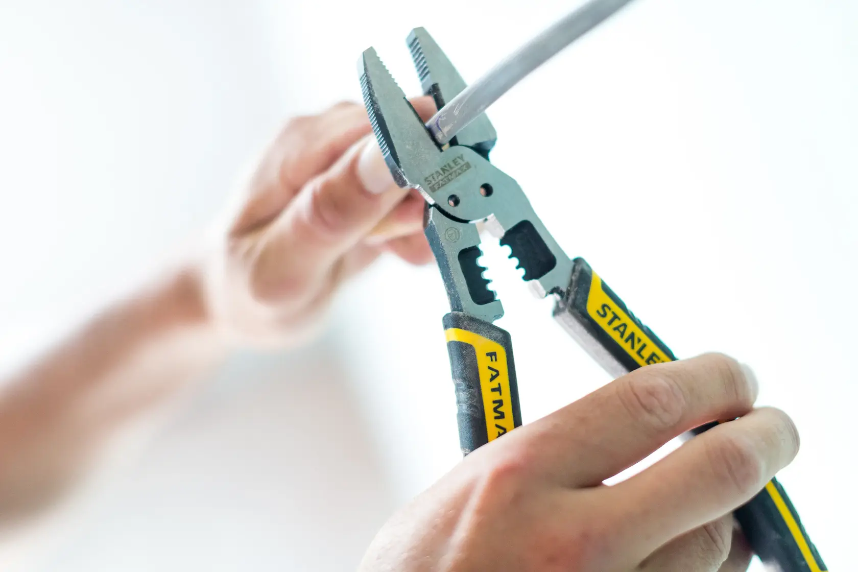 STANLEY FMHT0-75469 pliers with yellow handle gripping wire, close-up.