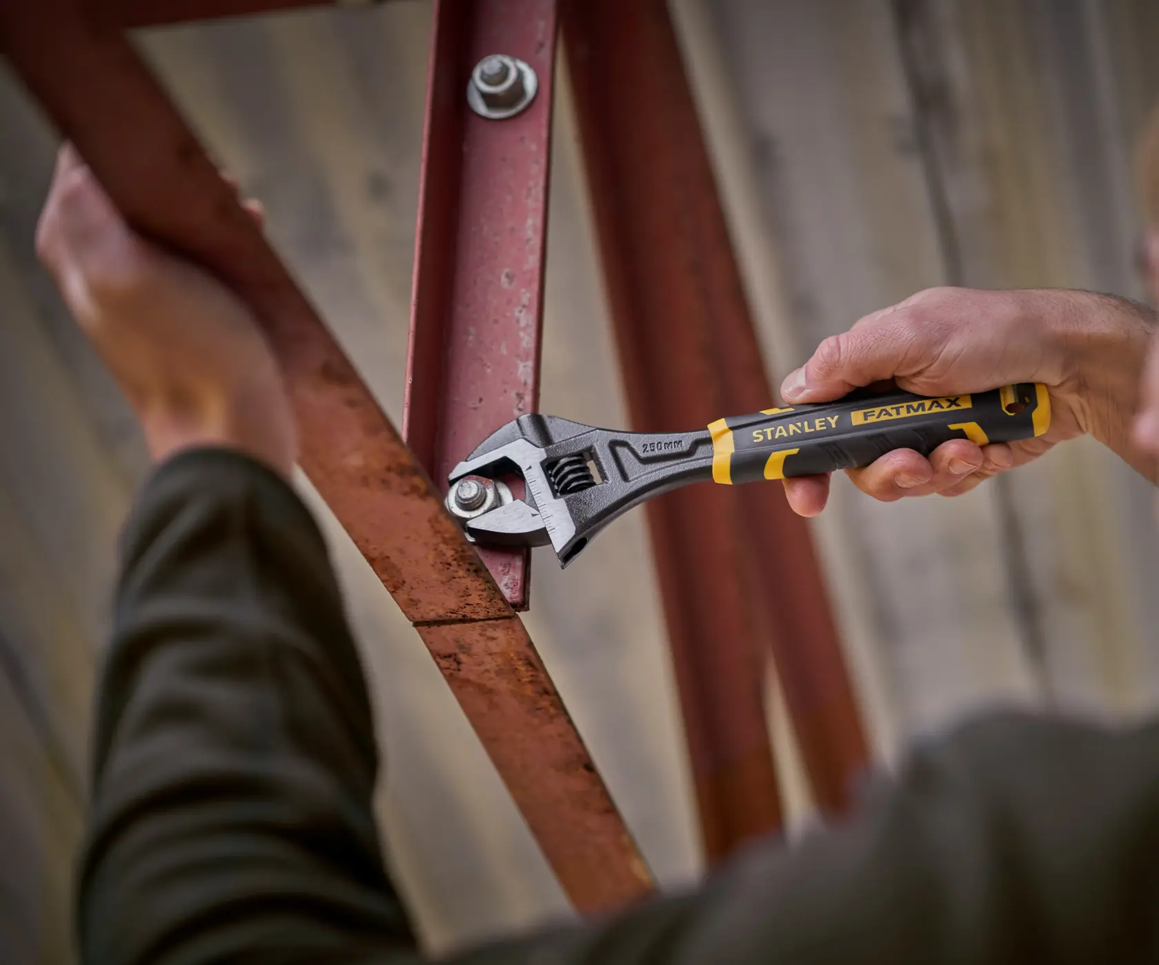 STANLEY FMHT13128-0 adjustable wrench, FATMAX series, used on a metal bolt, close-up photography.