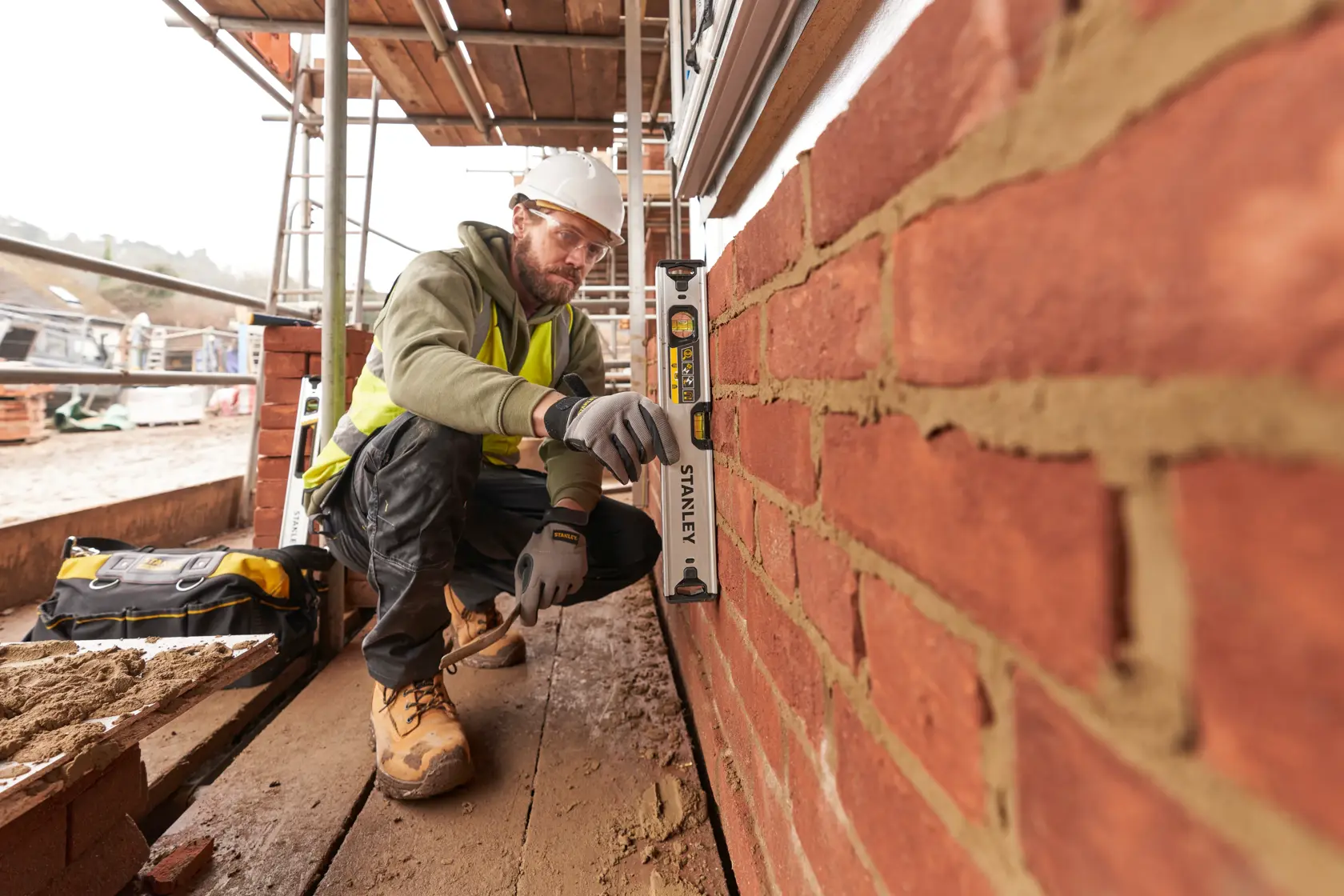 Photo of a worker using a STANLEY FMHT43671-1 spirit level on a brick wall at a construction site.