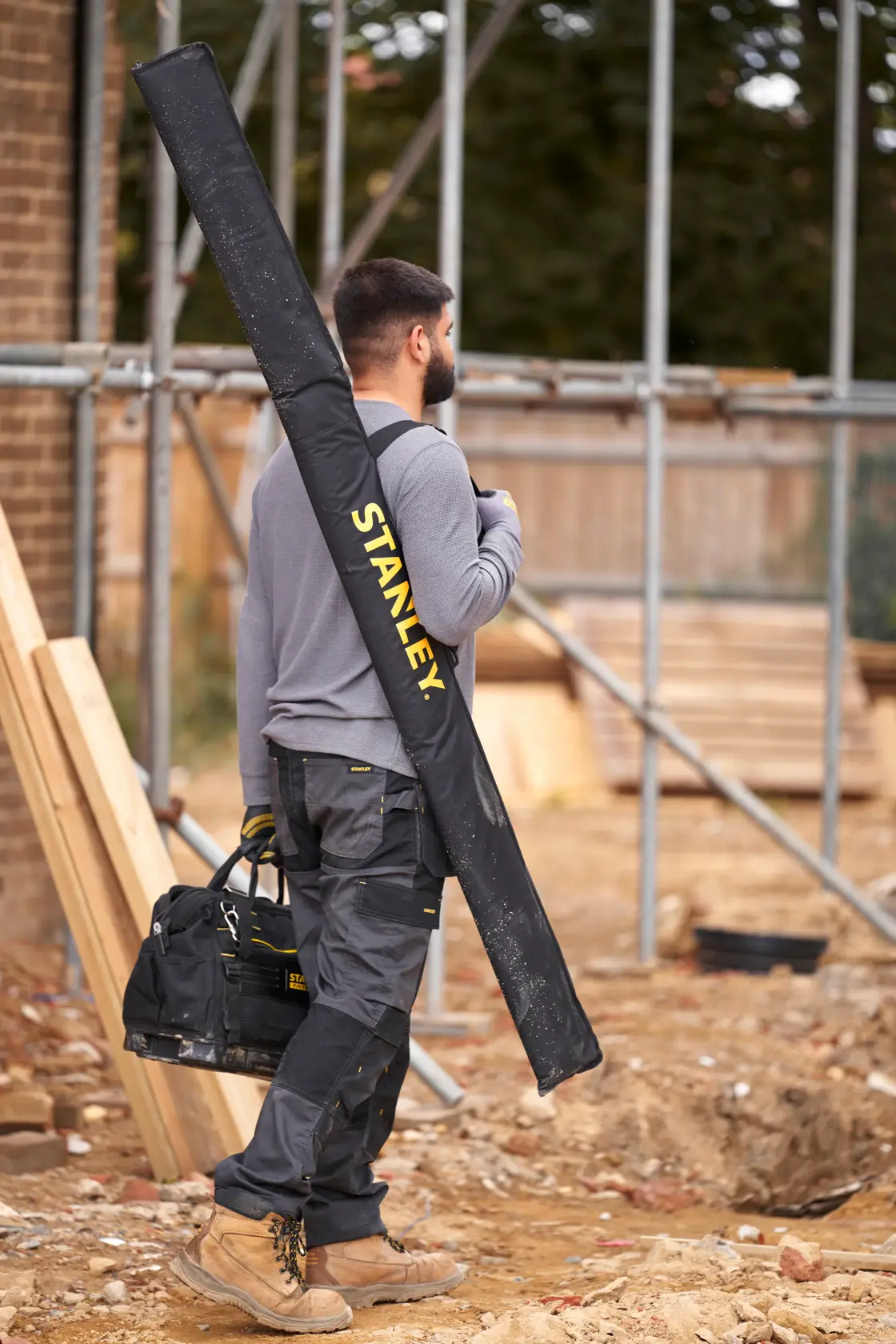 STANLEY FMHT43685-1 carrying case for tools in use on a construction site, shown over shoulder from side.