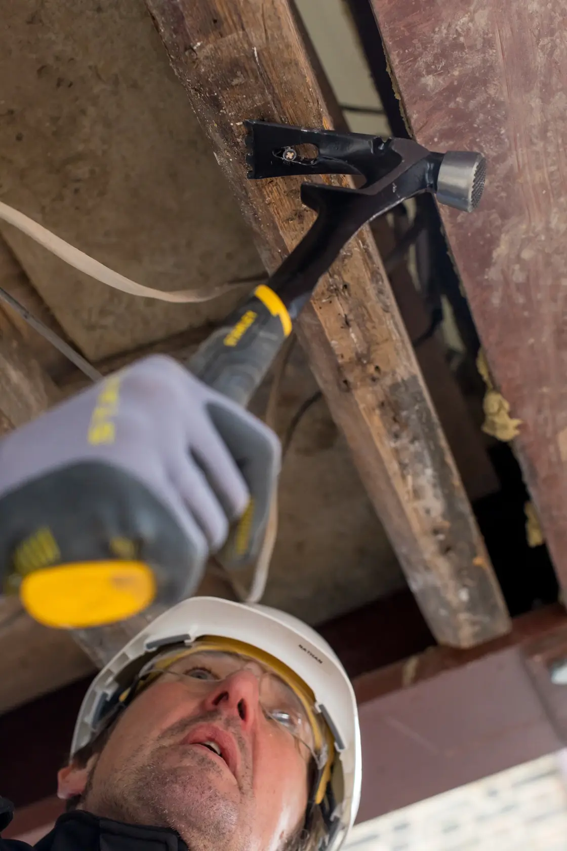 STANLEY FMHT51367-2 hammer used in construction, close-up angle showing striking head and black handle.