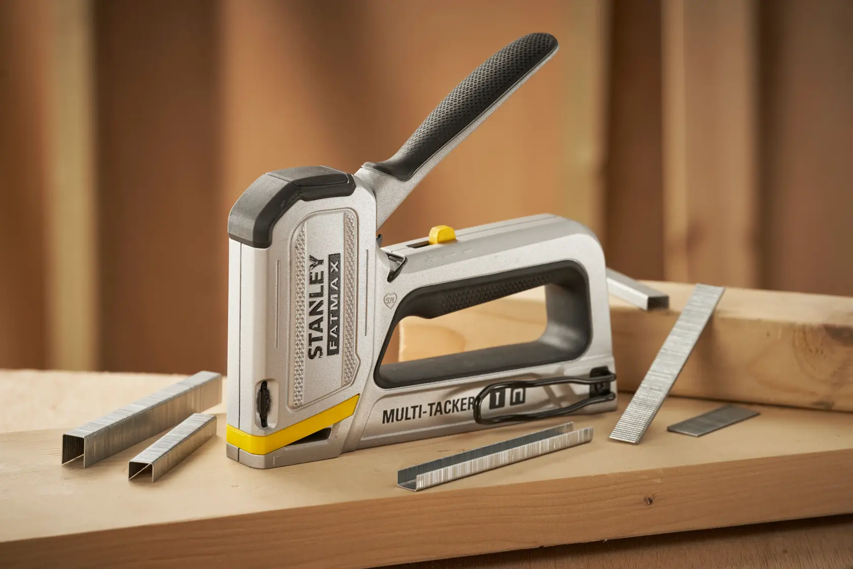 Stanley FMHT70250-0 stapler tool with staples on a wooden surface, FATMAX Multi-Tacker ergonomic handle.