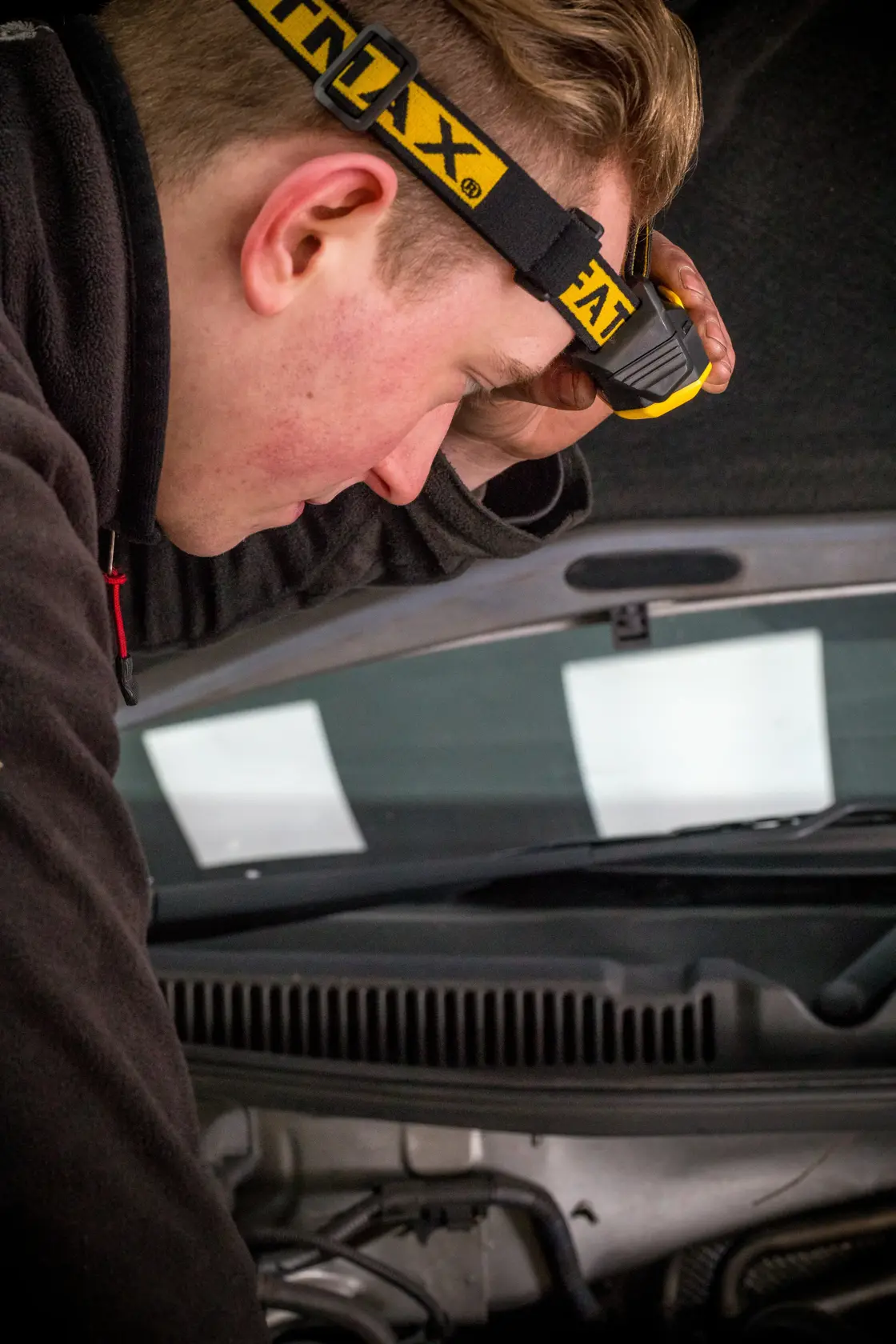 STANLEY FMHT81509-0 headlamp used by mechanic working under car hood, close-up photography.