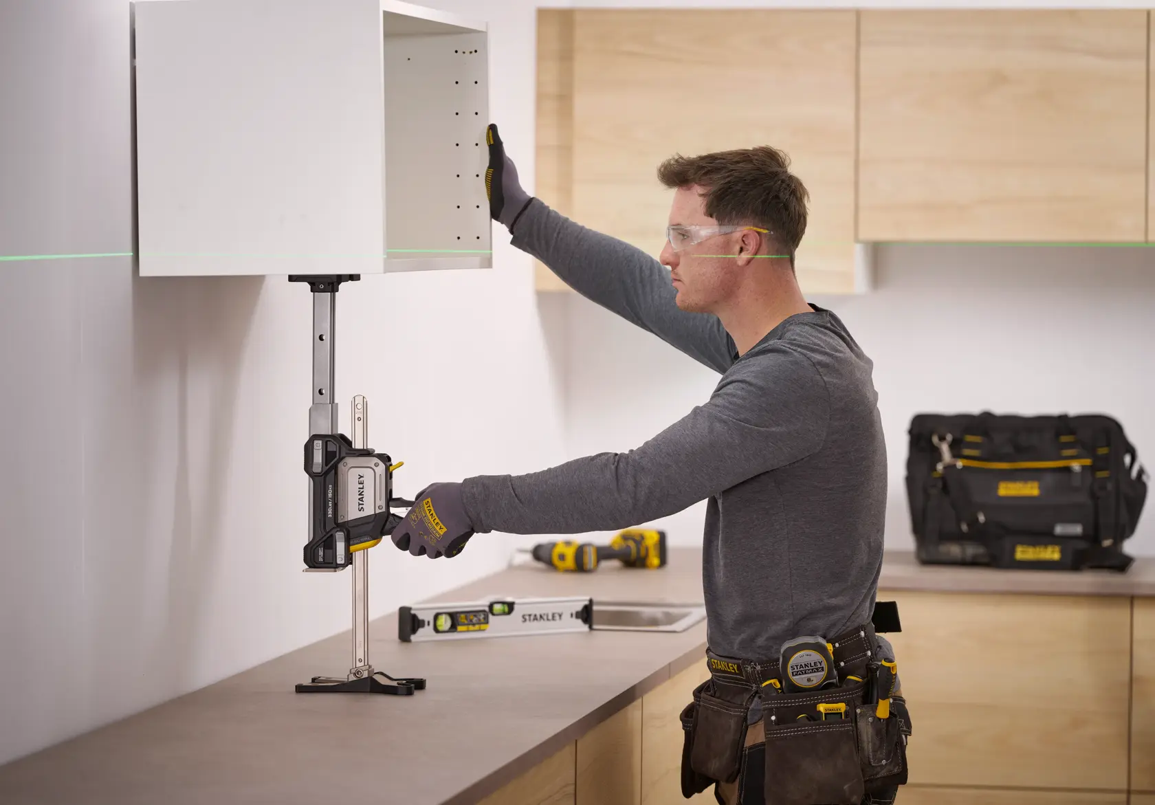 STANLEY FMHT83554-1 cabinet support clamp in use, holding a wall cabinet during installation, side angle.