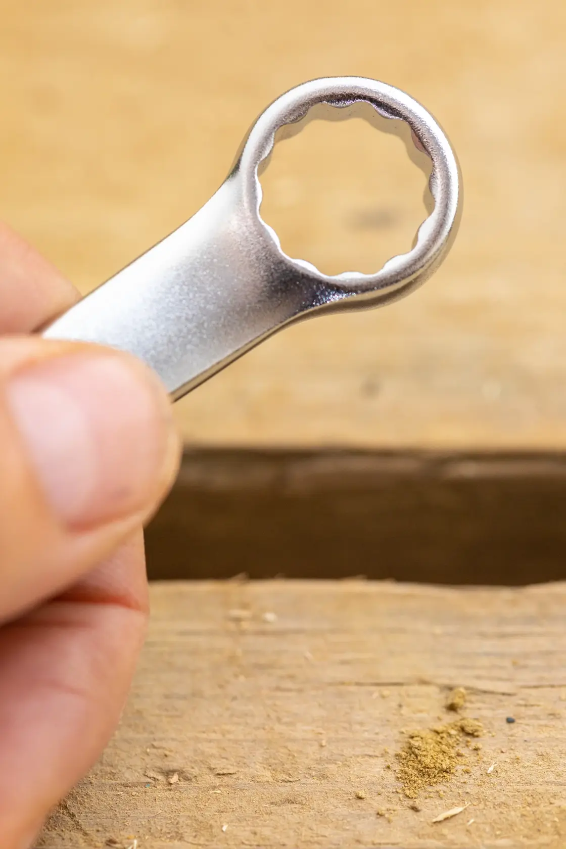 STANLEY FMMT13037-0 box-end wrench held in hand, close-up, silver finish, wooden surface background.