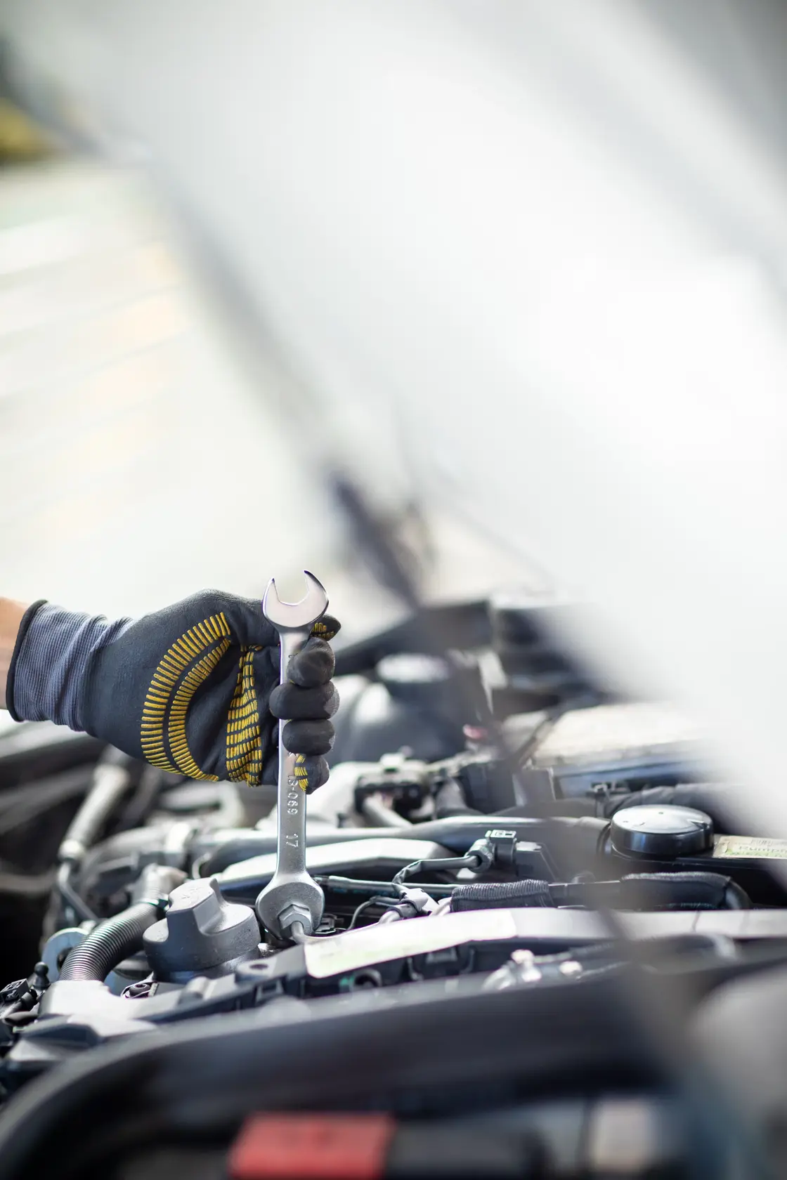 STANLEY FMMT13068-0 wrench held by gloved hand working on car engine, close-up photography.