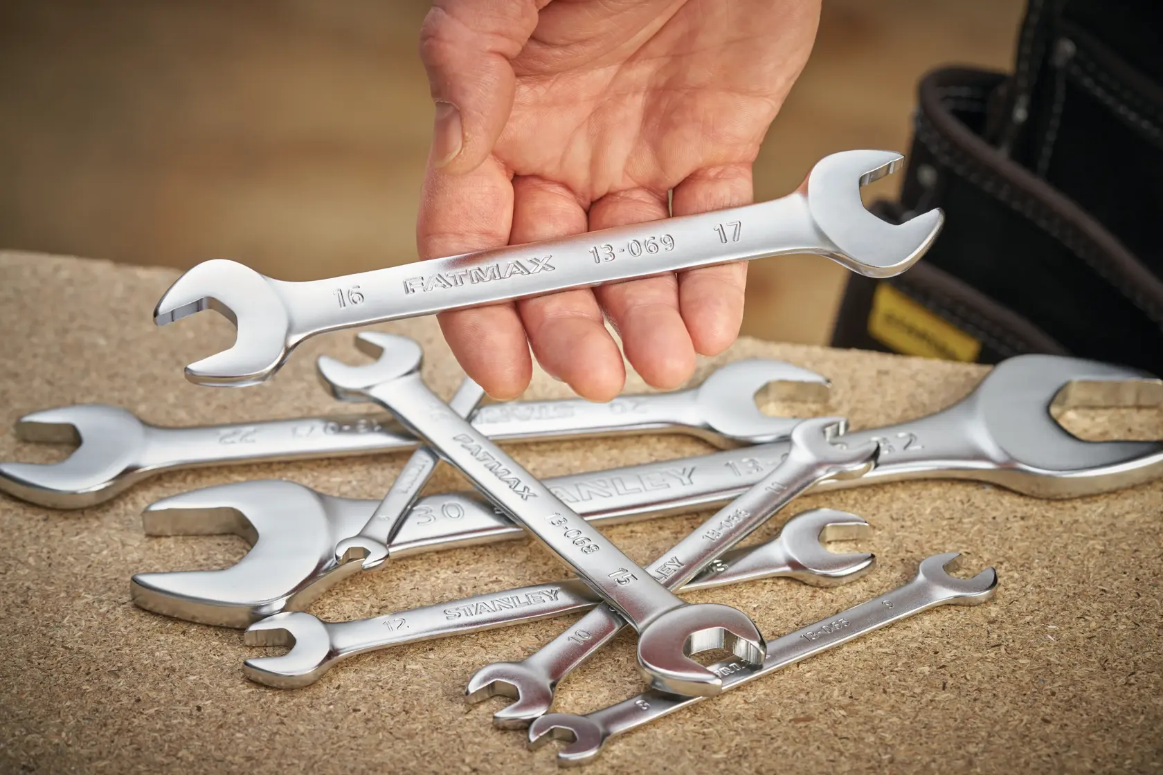 STANLEY FMMT13070-0 photography of chrome wrenches, one held in hand, others scattered on work surface.