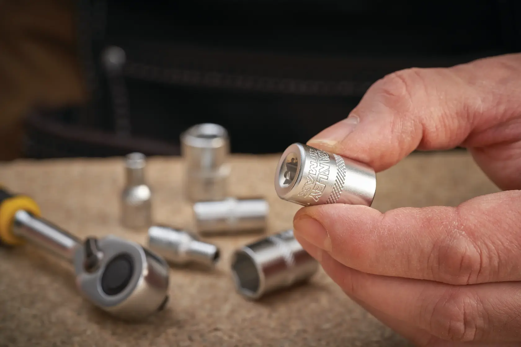 Photo of STANLEY FMMT17191-0 socket held in hand, with ratchet and other sockets on work surface.