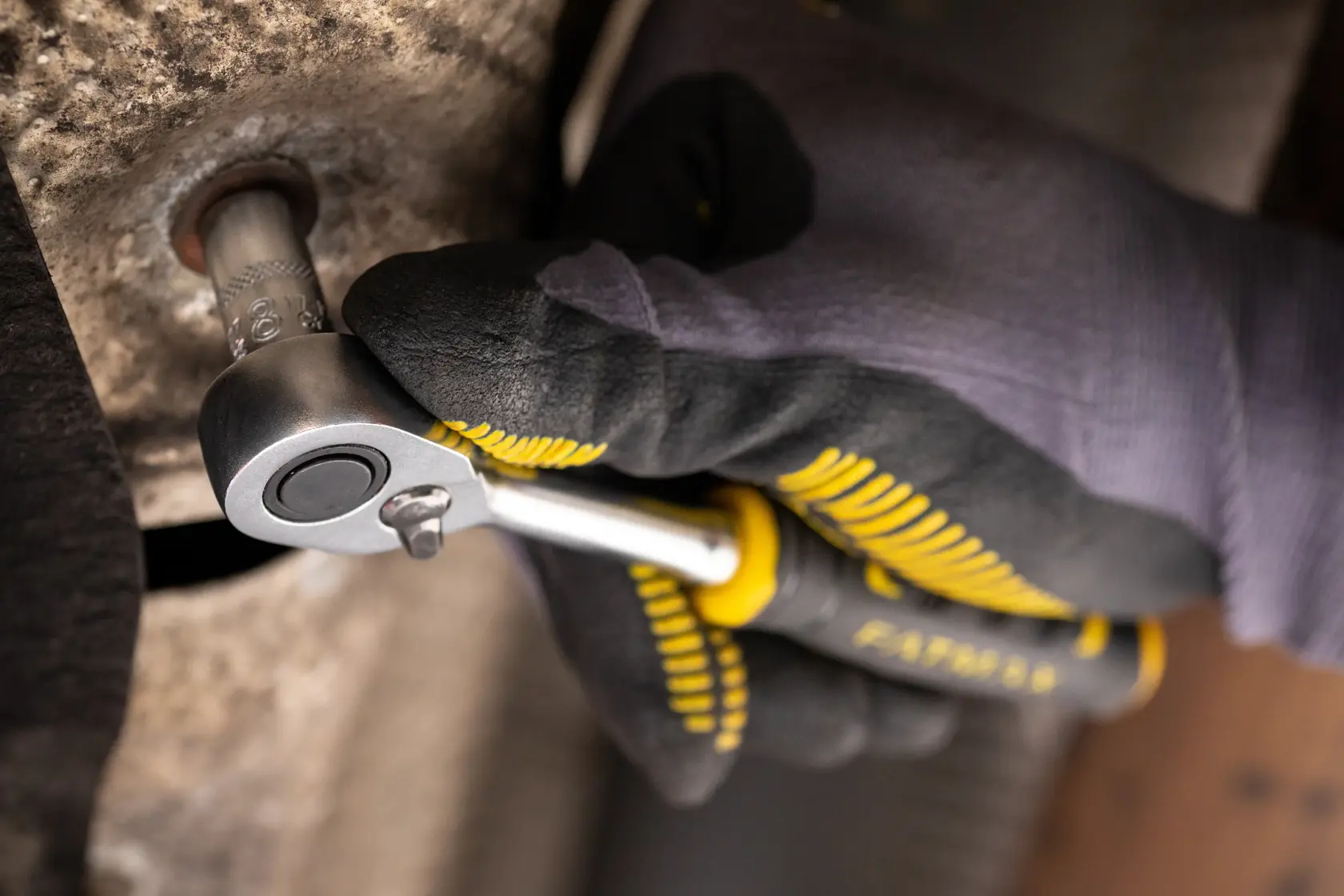 STANLEY FMMT17197-0 ratchet wrench in use, close-up showing hand with glove turning metal bolt.