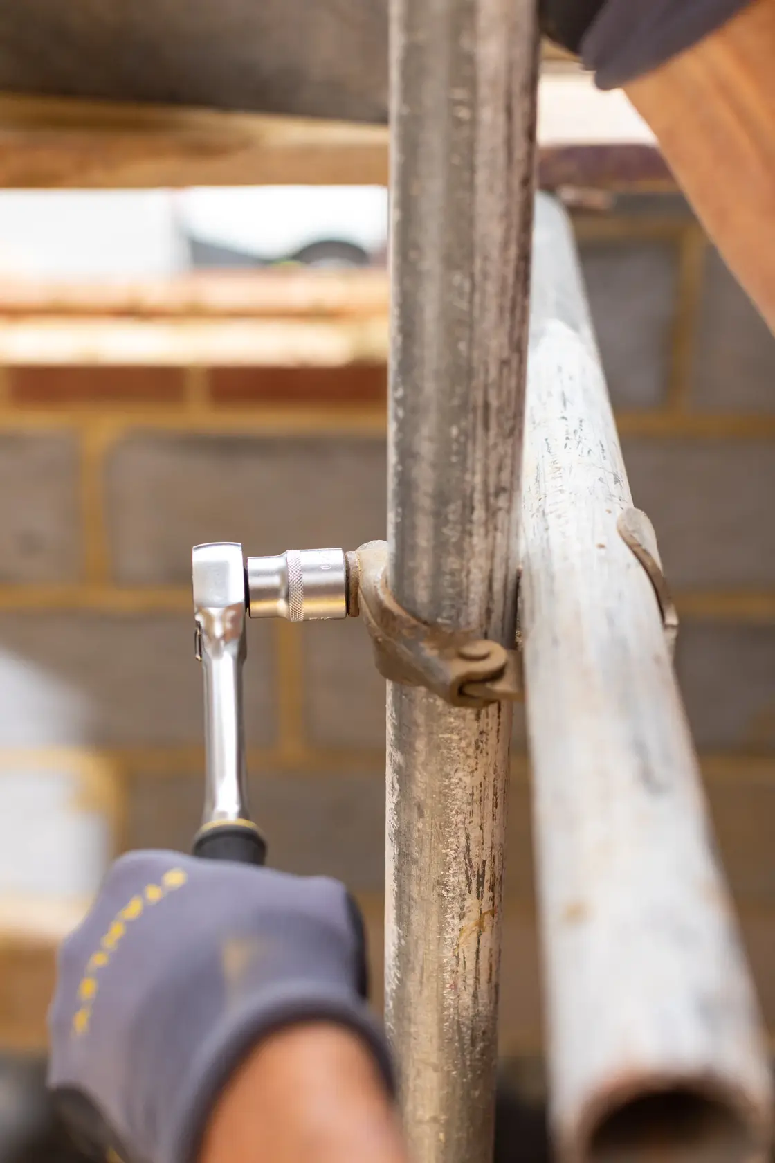 STANLEY FMMT17245-0 ratchet tool in use tightening scaffold pipe clamp, close-up photography.