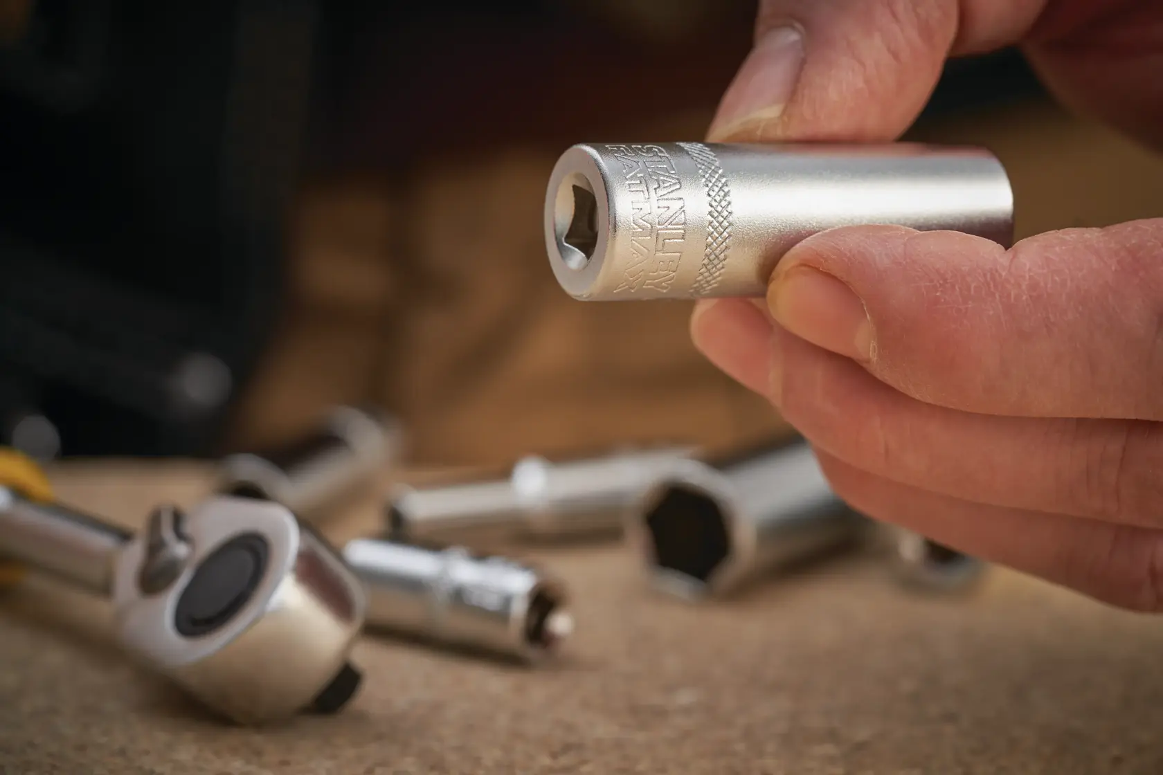 STANLEY FMMT17248-0 socket held in hand, close-up with other sockets and ratchet on work surface.