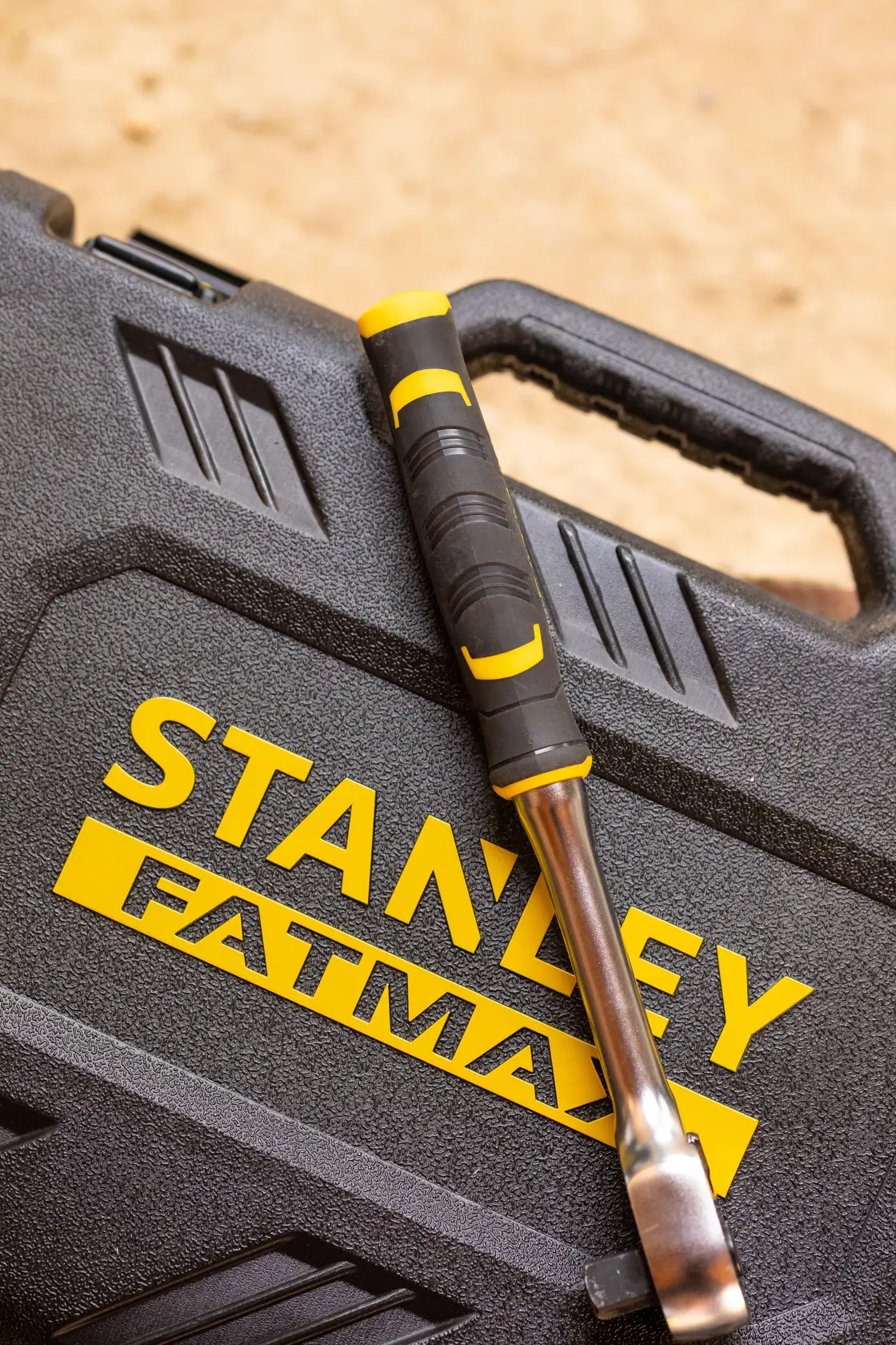 STANLEY FATMAX FMMT82684-1 ratchet with black and yellow handle resting on textured toolbox, angled view.
