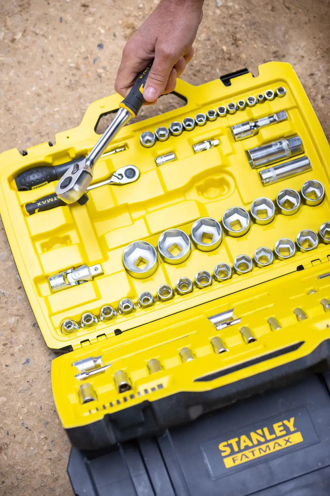 STANLEY FMMT82826-1 socket and ratchet set with yellow case, hand holding ratchet, top-down view.