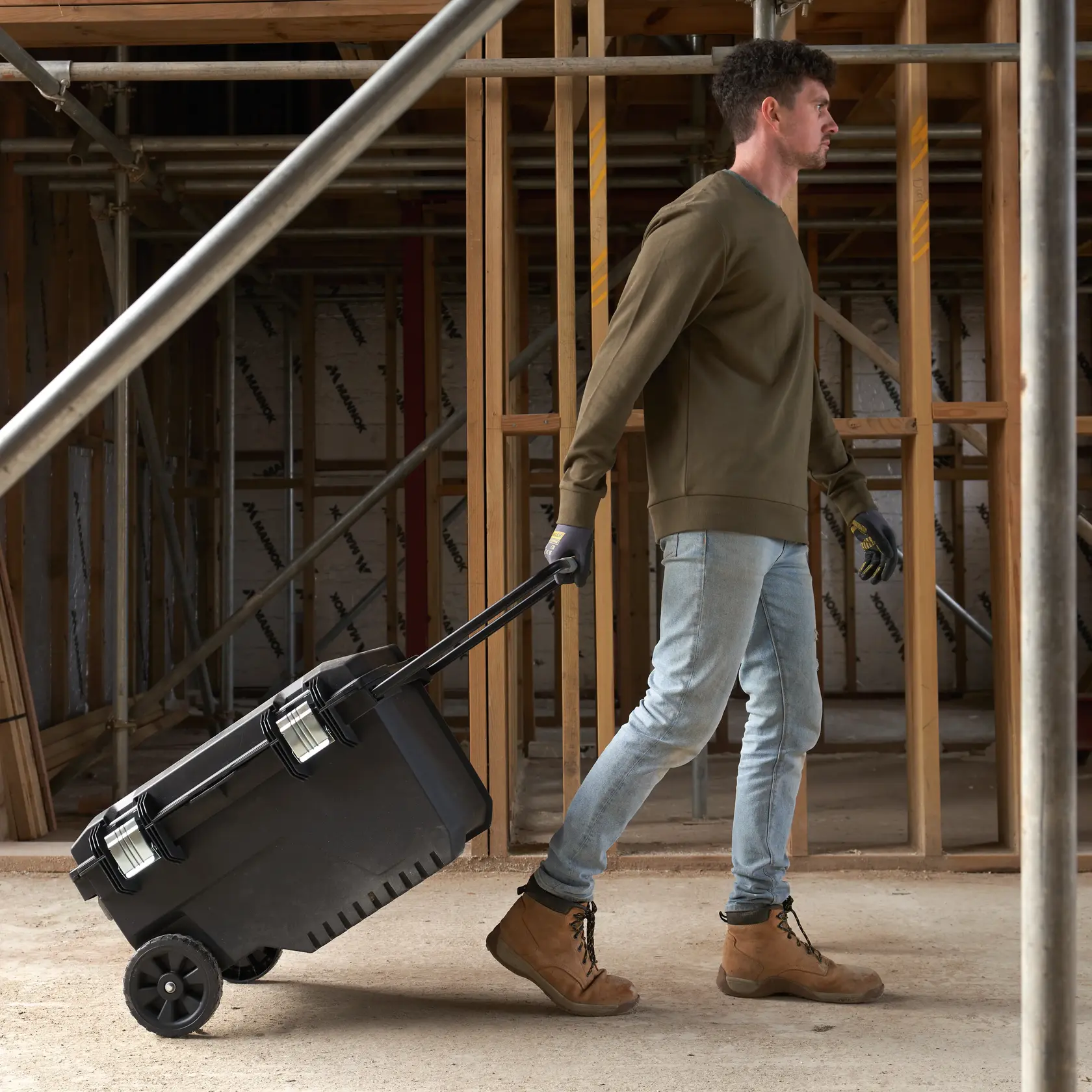 STANLEY FMST1-73601 rolling tool box pulled by a worker at a construction site.