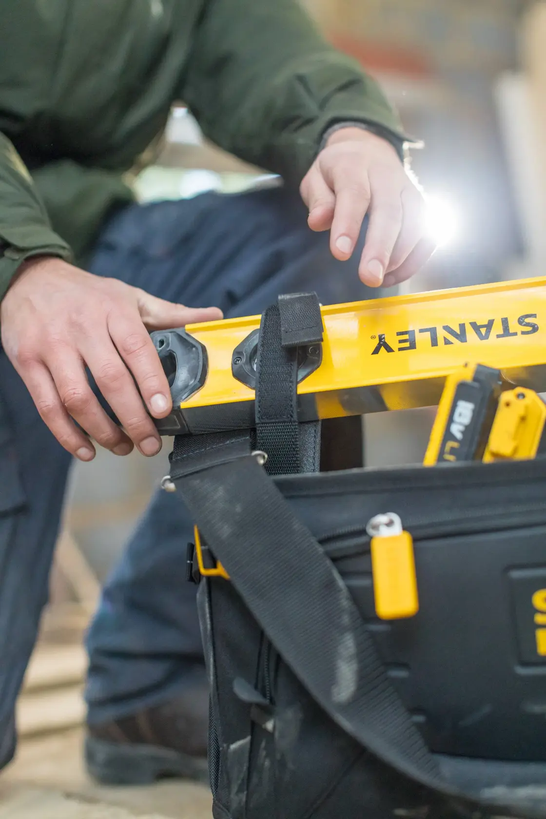 STANLEY FMST1-80146 tool bag with tools and yellow level, close-up, photographer captures use on site.