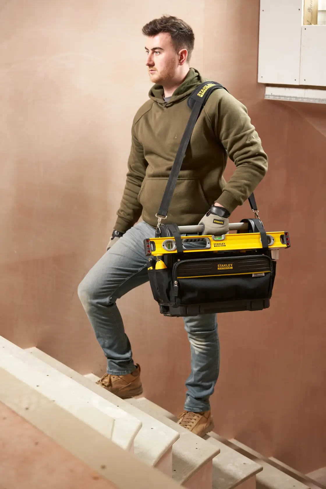 STANLEY FMST17626-1 tool bag with tools, carried by person on stairs, front angle photography.