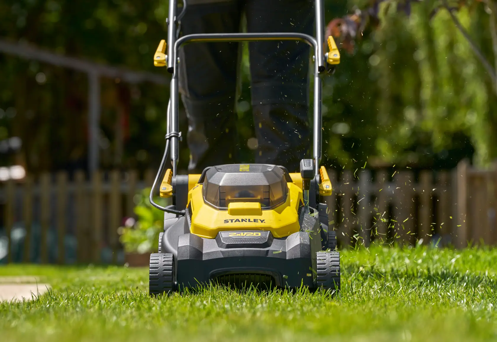 STANLEY SCMWP3701M2 cordless lawn mower front view cutting grass outdoors.