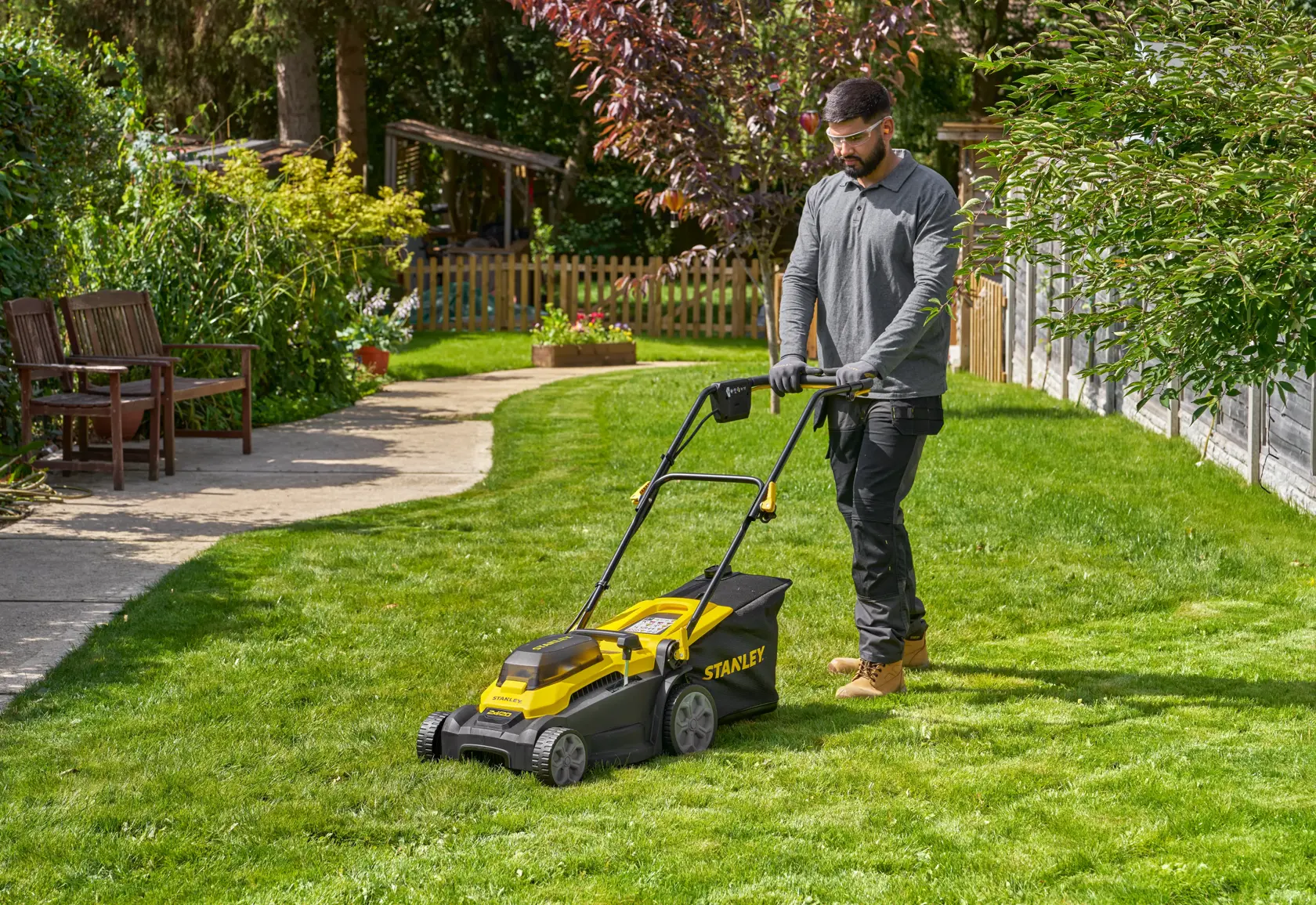 STANLEY SCMWP3701N lawn mower in use on green lawn with person pushing, outdoor garden setting.