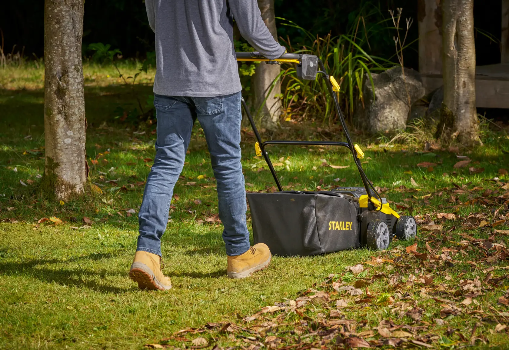 Photo of STANLEY SCOEP3801N lawn mower with rear grass bag being pushed on grassy yard.