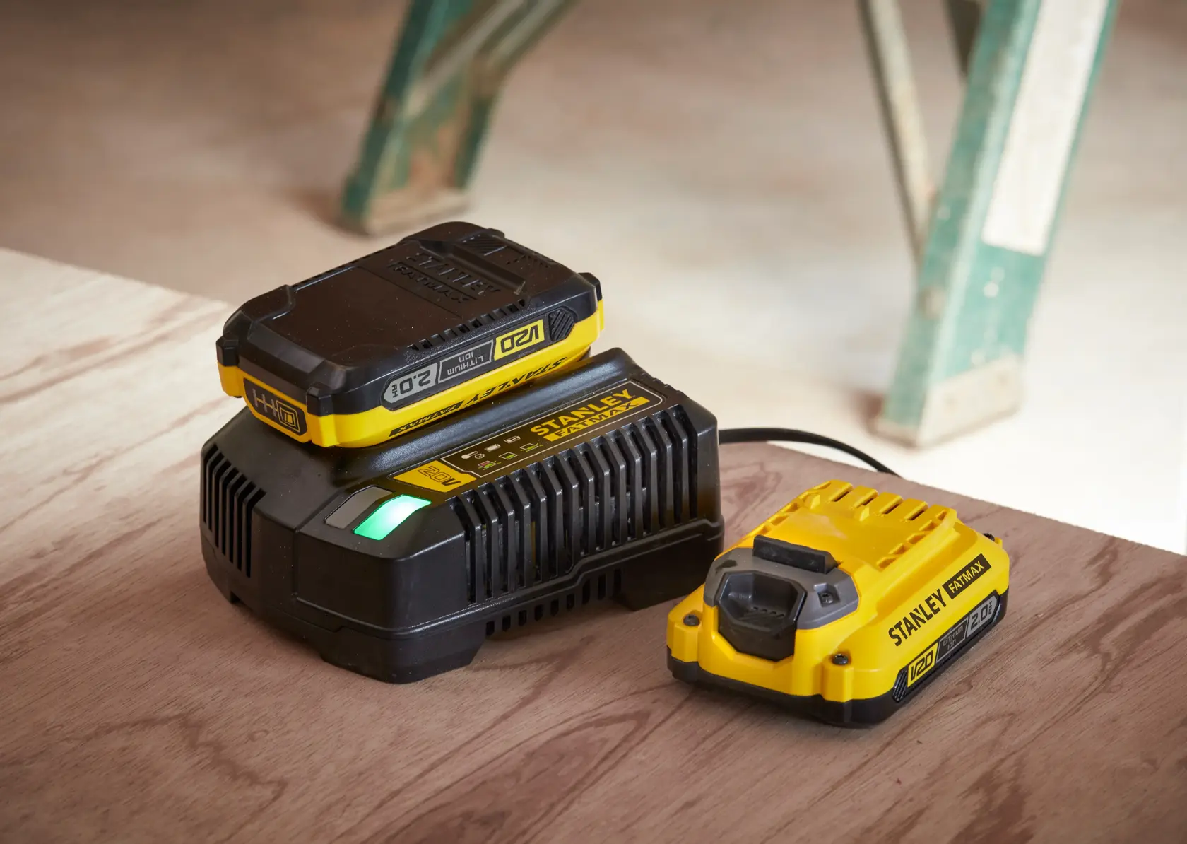 Photo of STANLEY SFMCB12D2 battery charger and battery pack in yellow and black on a wooden surface.
