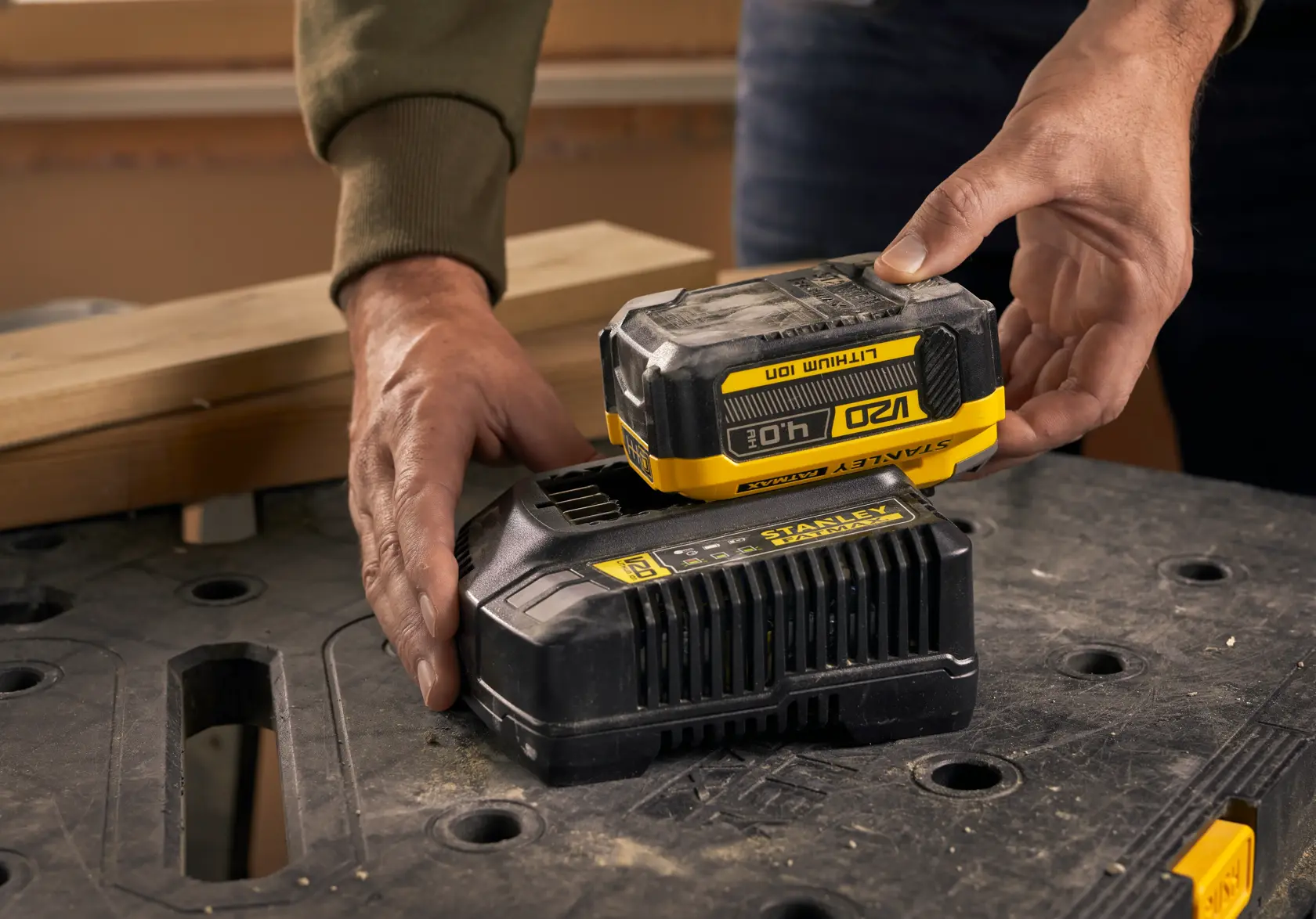 Foto der STANLEY SFMCB14M1 18V Lithium-Ionen-Batterie auf einem Ladegerät, auf einer Werkbank gezeigt.