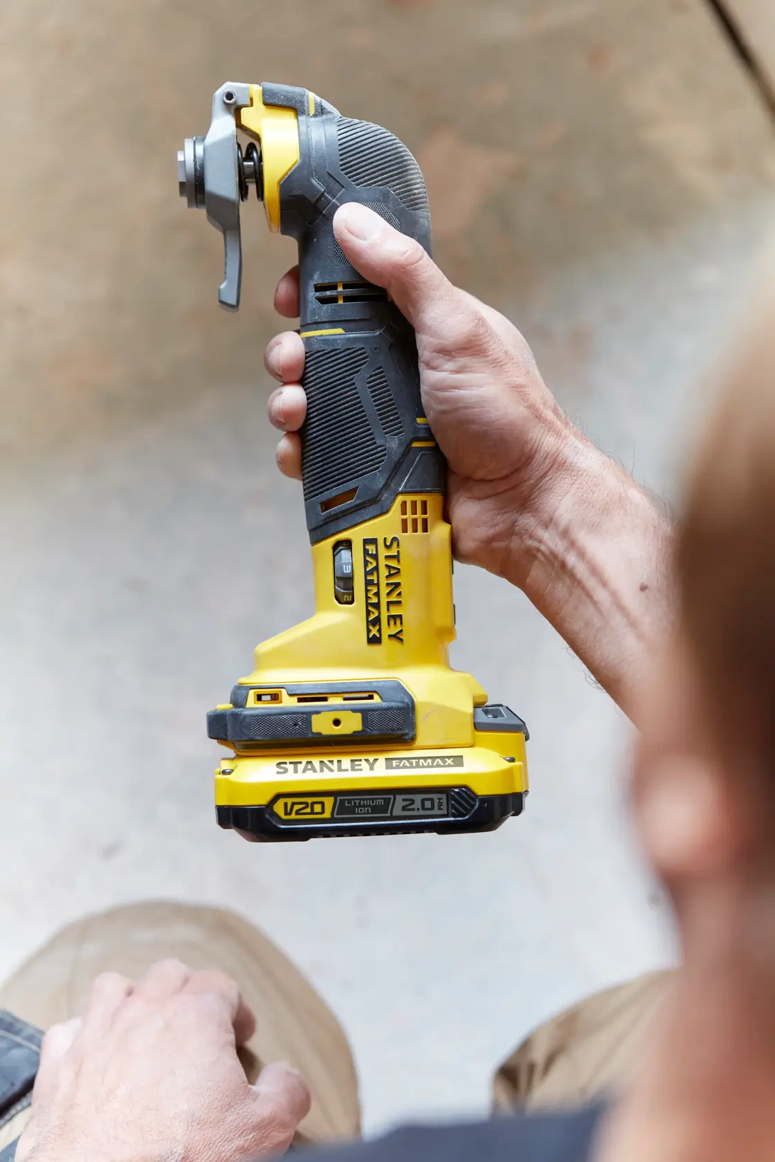 Photo of STANLEY SFMCE500D2K cordless multi-tool held in hand, yellow and black construction.