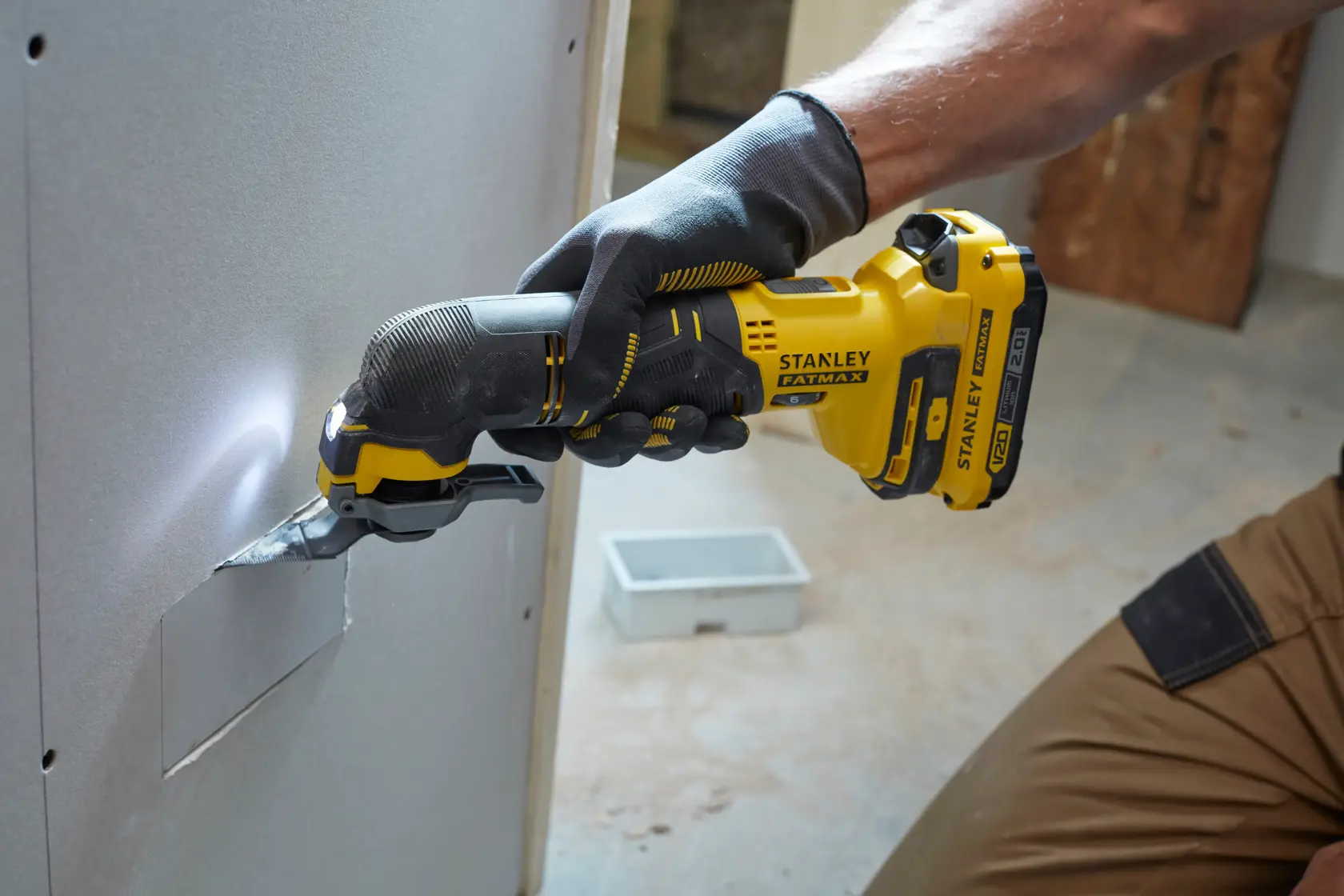 Photo of STANLEY SFMCE500D2K oscillating multi-tool in use cutting drywall, shown from the side.