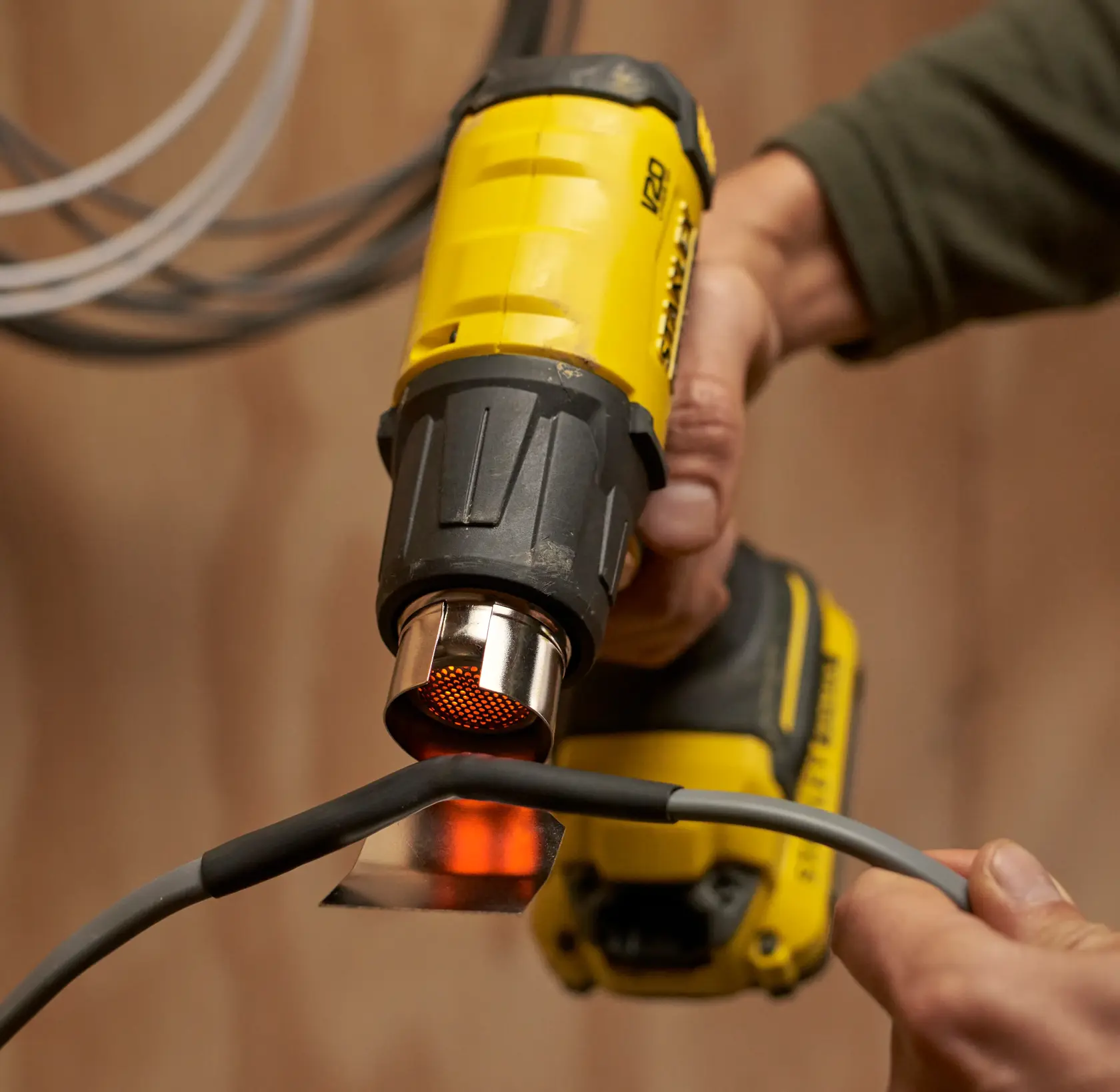 Photo of STANLEY SFMCE530B cordless heat gun in use heating a cable.