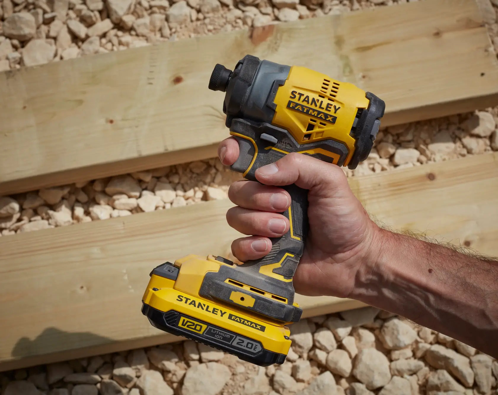 STANLEY SFMCF810D2K impact driver, yellow and black, handheld, shown outdoors on wood and gravel.