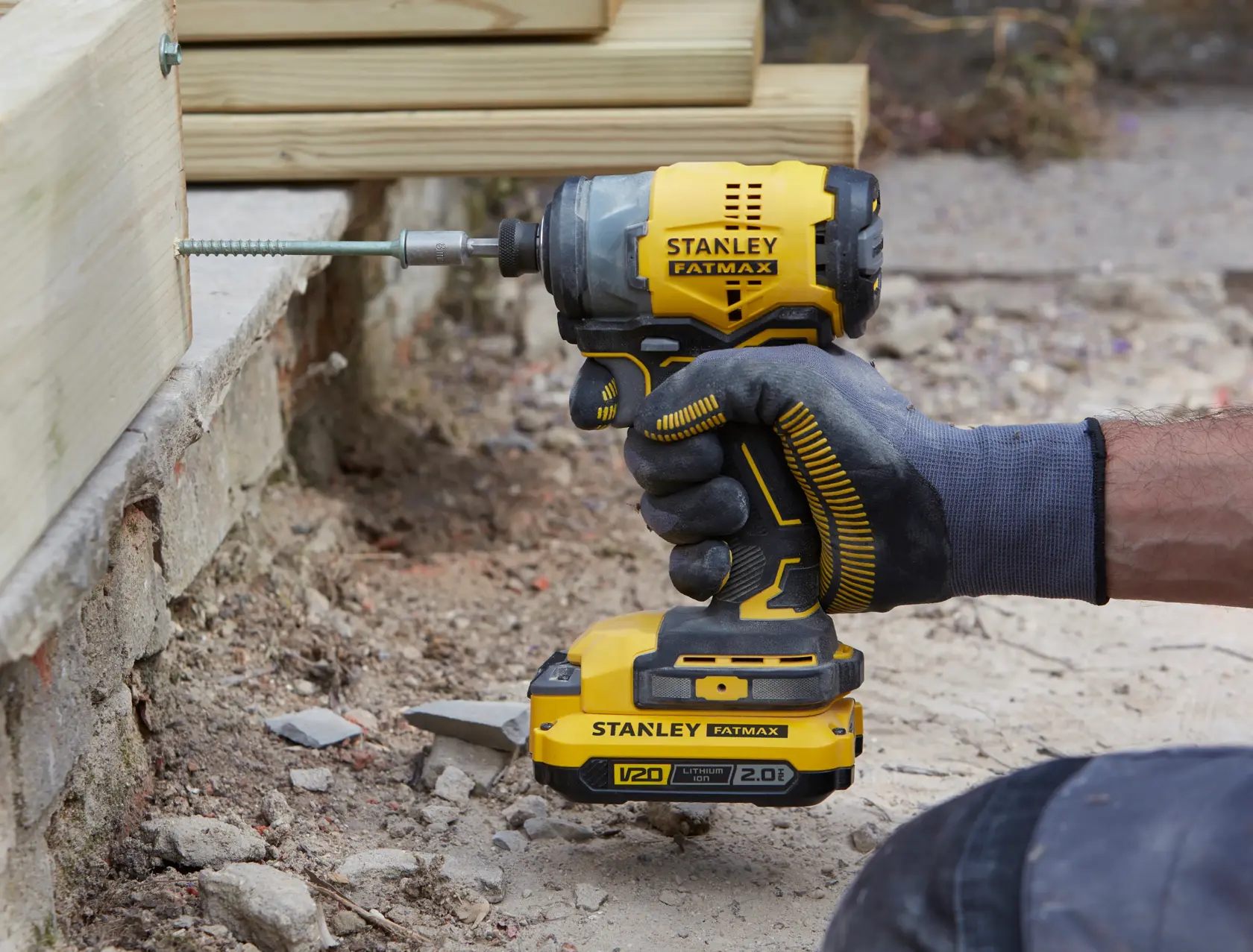Photo of STANLEY SFMCF820D2K cordless impact driver in use, yellow and black design, driving screw into wood.