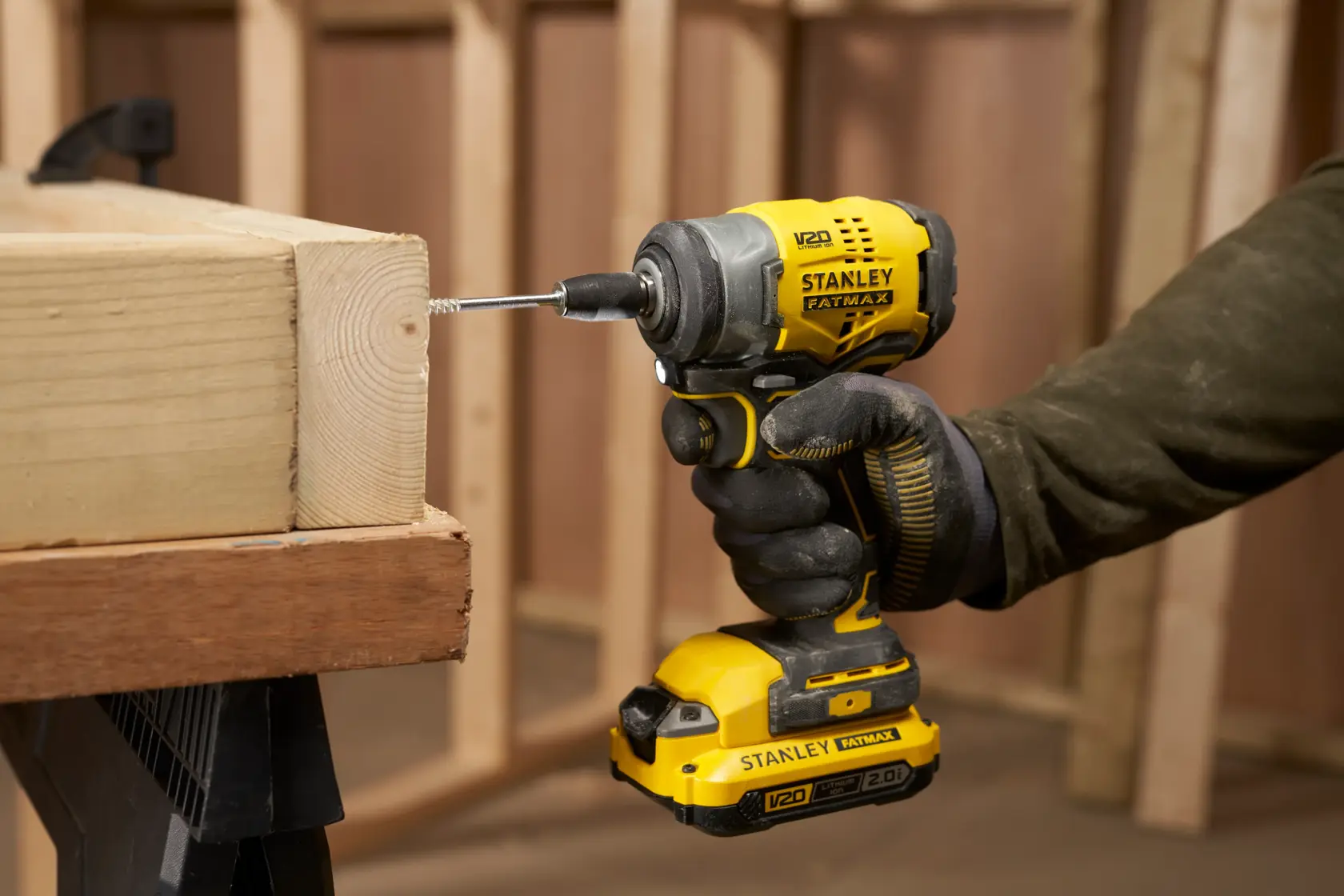 STANLEY SFMCF910B impact driver in yellow and black, drilling into wood, close-up side view.