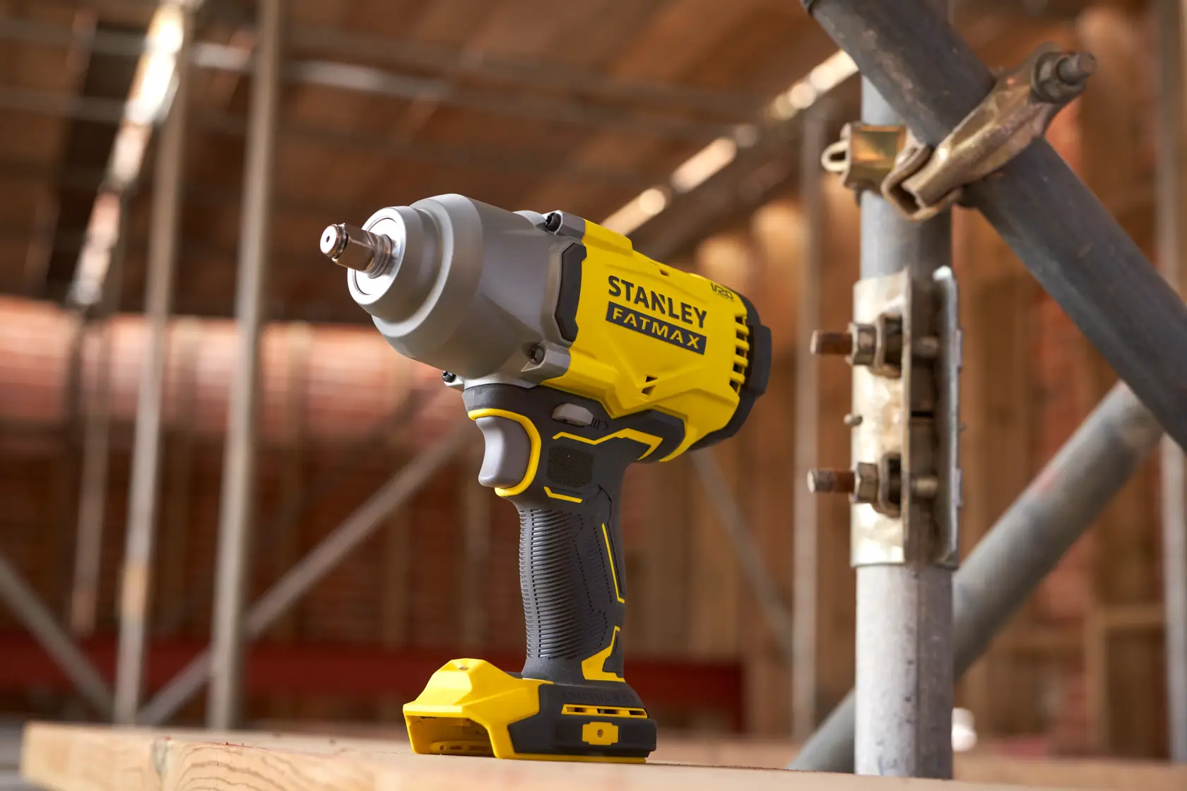 STANLEY SFMCF940M1 cordless impact wrench on construction site, yellow and black body, side view.