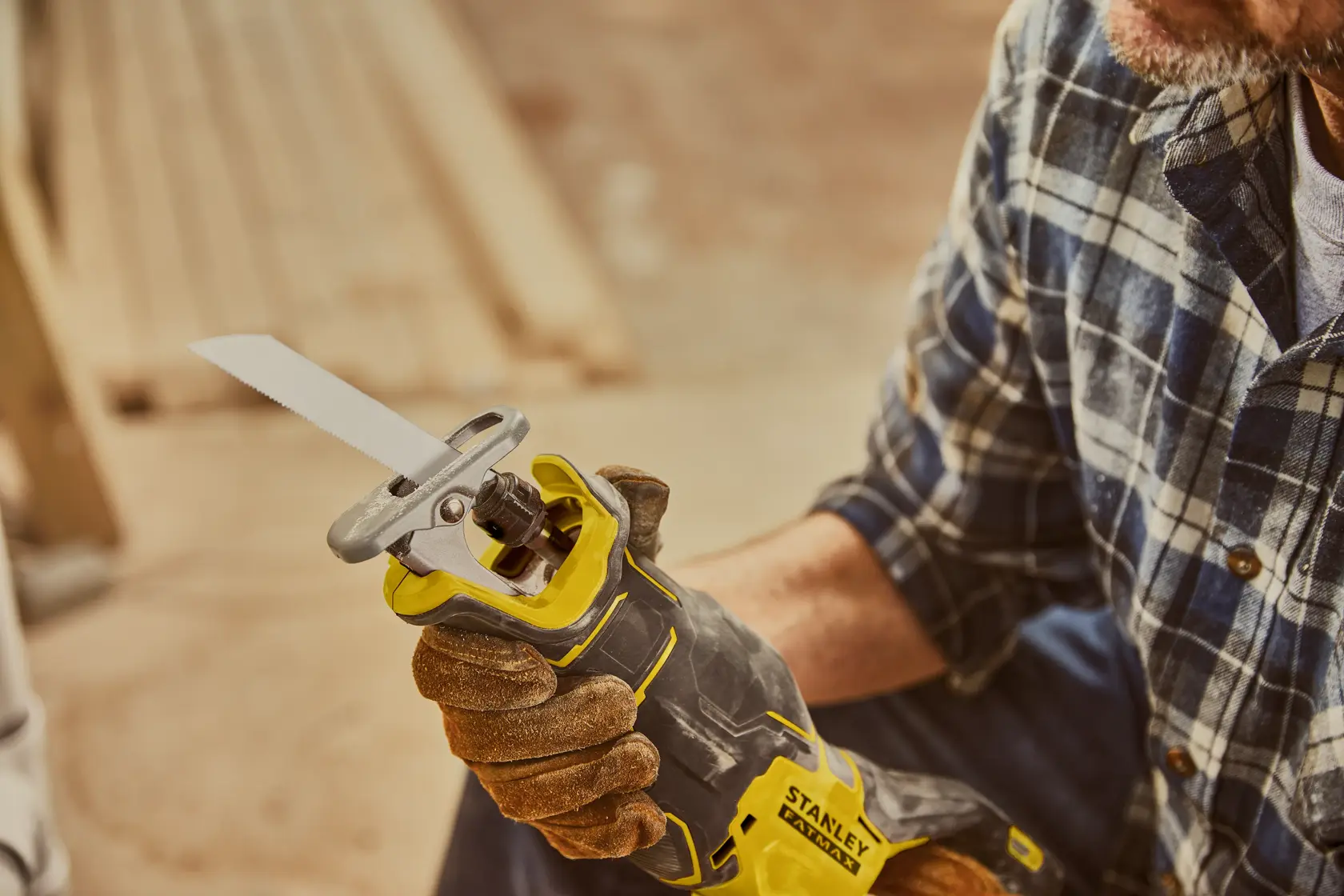 Photo of STANLEY SFMCG700B cordless reciprocating saw held by a person wearing work gloves and plaid shirt.