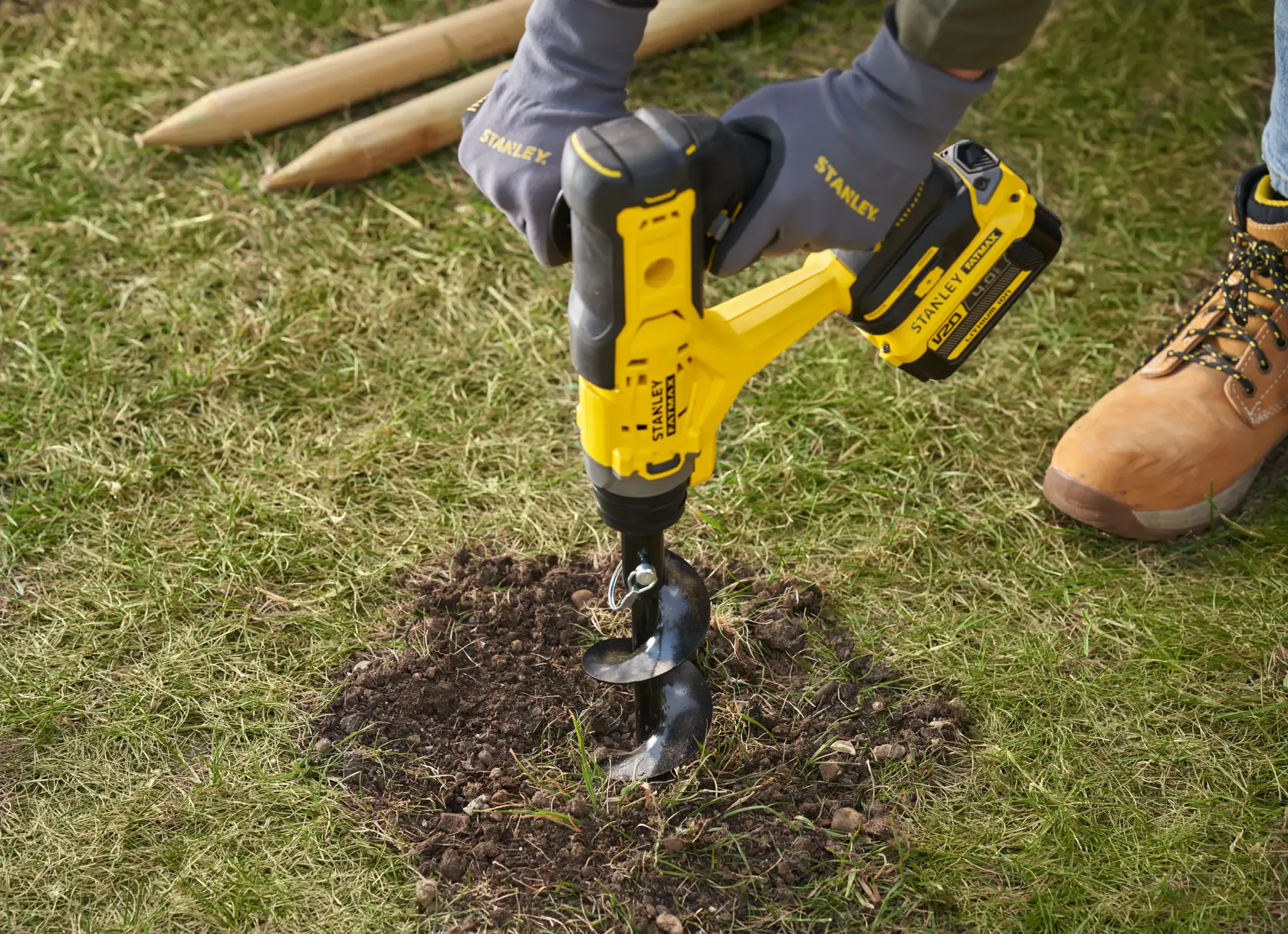 STANLEY SFMCGA75M1 cordless garden auger drilling into soil, close-up outdoor scene.